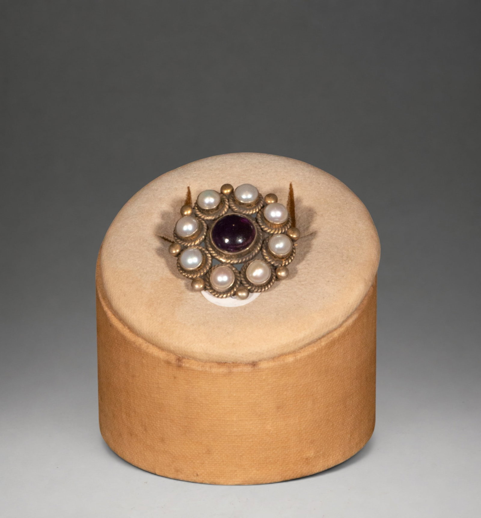 Silver-gilt brooch with amethyst and pearls: Circular brooch in gilt-plated silver with a central amethyst cabochon surrounded by radially mounted pearls. A simple and elegant design, inspired by classic style.