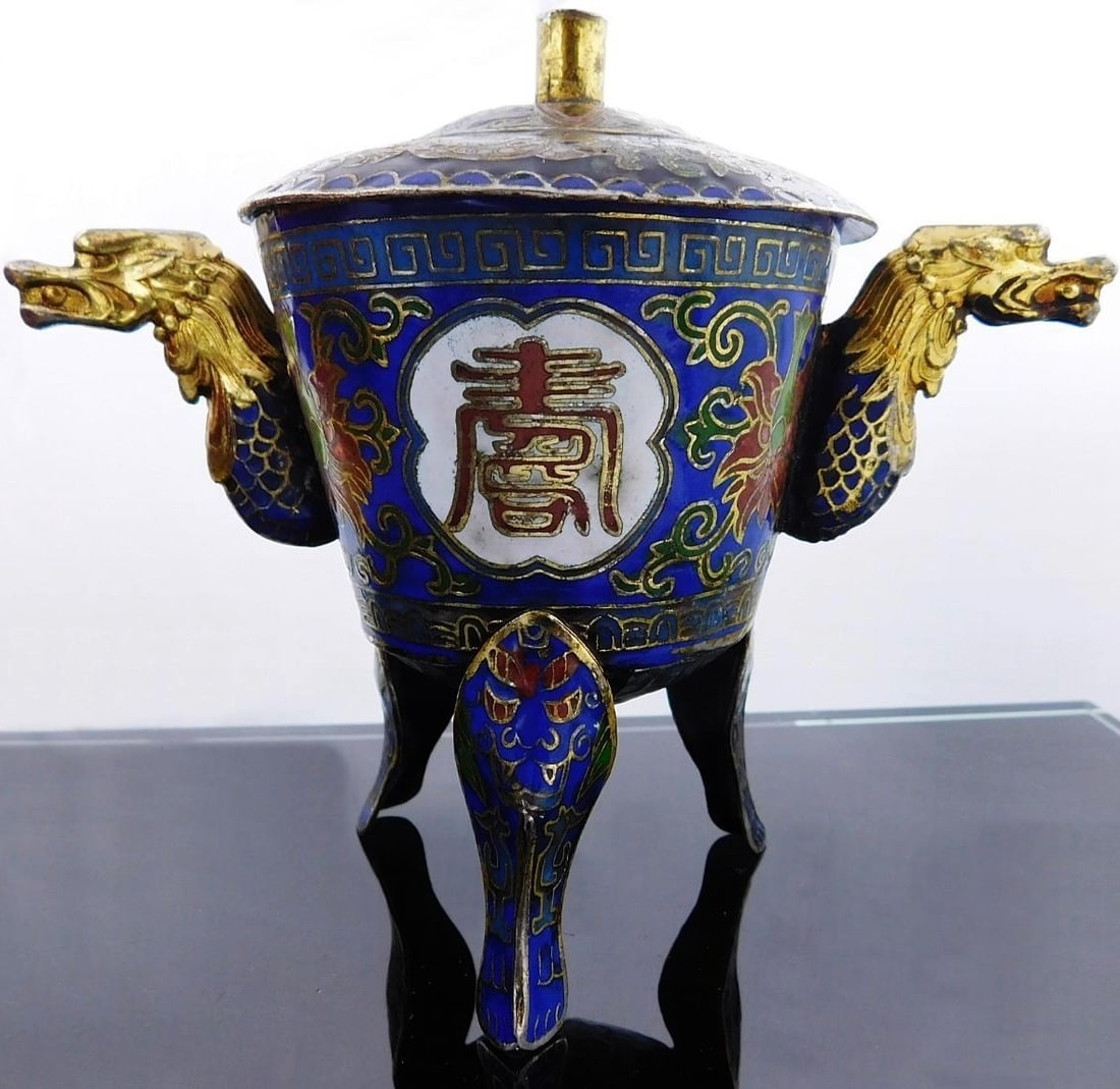Chinese three-legged incense burner with cloisonné enamel, Chinese, 20th century: Antique Chinese three-legged incense burner with lid, dragon-head shaped side handles, and cloisonné enamel decoration, reliefs, and gilding. Made of bronze with motifs of dragons, symbols, flowers, 