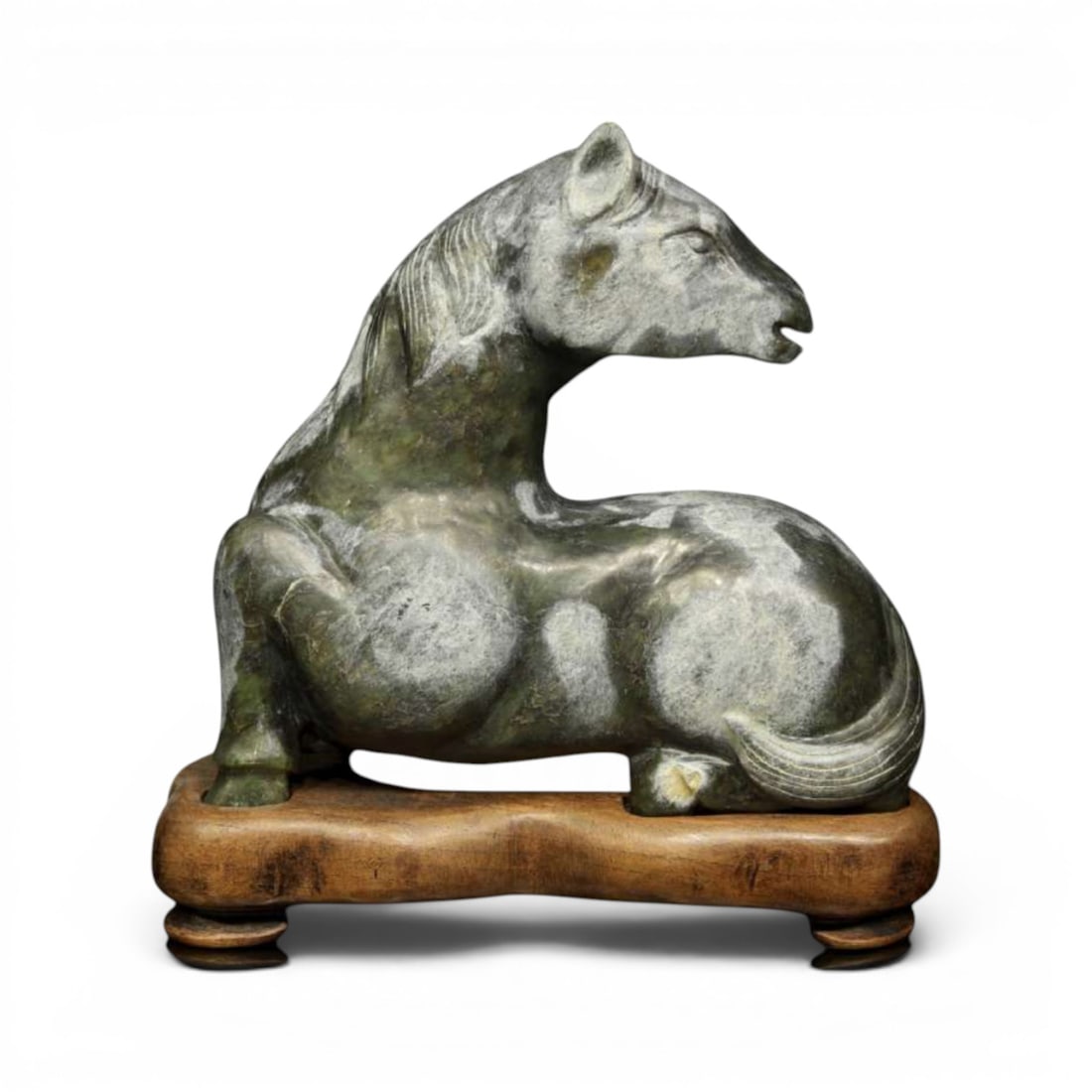 Horse reclining on hard stone. China, 20th century or earlier: Chinese sculpture carved from hard stone, depicting a horse reclining on a carved wooden base. The figure shows the animal in a resting position, with its head turned, legs tucked under its body, and 