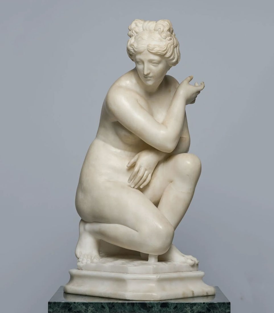 Kneeling Venus, Italian Grand Tour sculpture in the Neoclassical tradition, 20th Century: Carved and polished white Carrara marble. Measurements: 51 x 25 x 23 cm. Nude female figure identified as Venus, shown kneeling upon a moulded base and conceived after models from Classical sculpture 