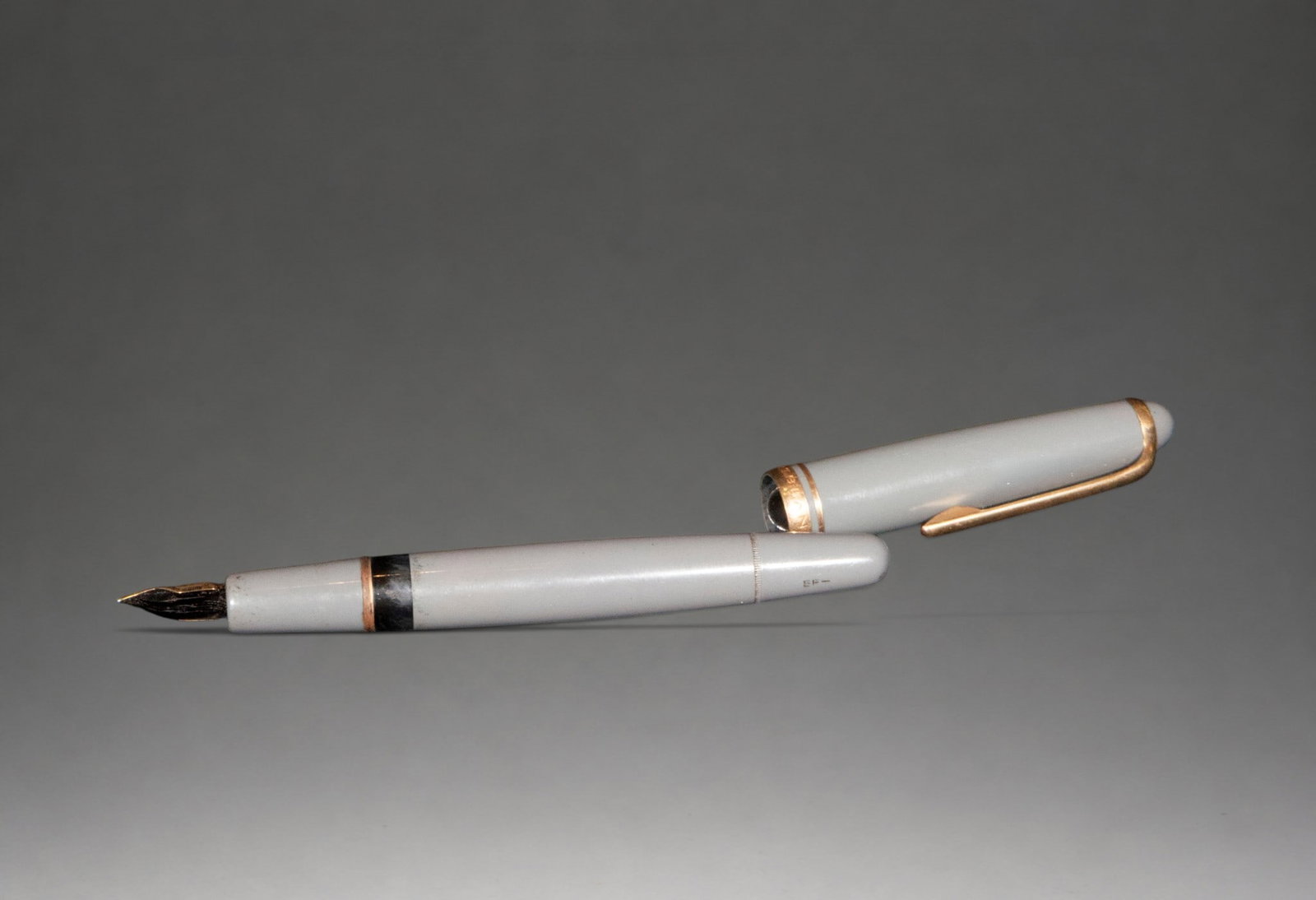 Montblanc fountain pen, German School, 20th century.: White resin with gold-tone metal accents and a gold nib. This writing instrument boasts a refined design, characterized by a cylindrical body with clean, elegant lines, finished in polished white resi