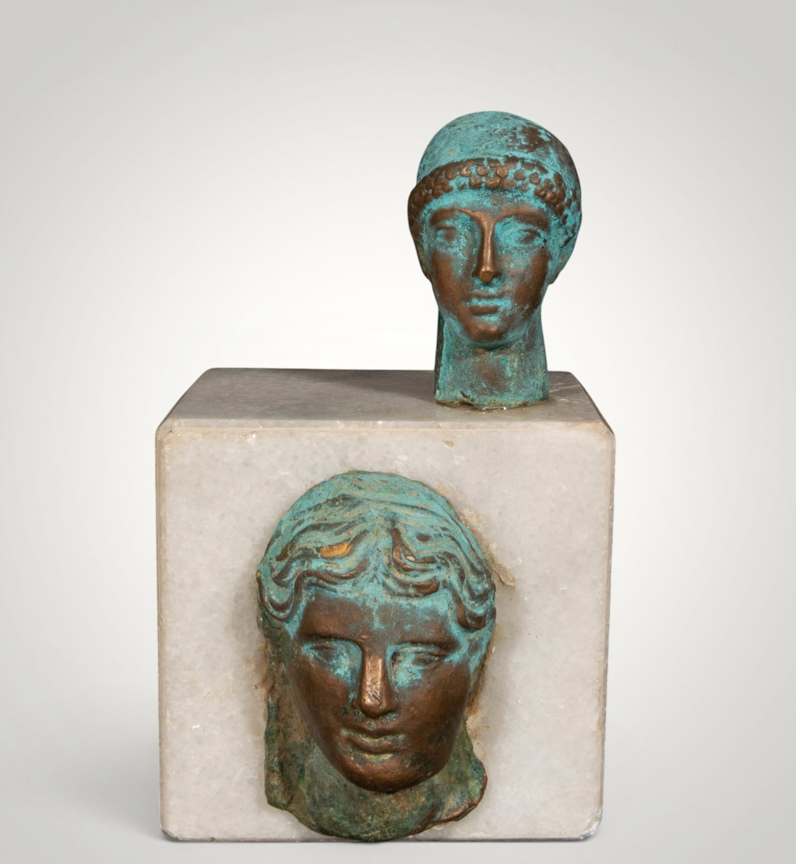 Pair of classical heads on a pedestal. Grand Tour style. Italian school. 19th century: Cast and patinated bronze on white marble. Measures 15 x 10 x 9 cm. Cabinet composition consisting of two classically inspired heads, one male and one female, mounted on a cubic white marble pedestal.