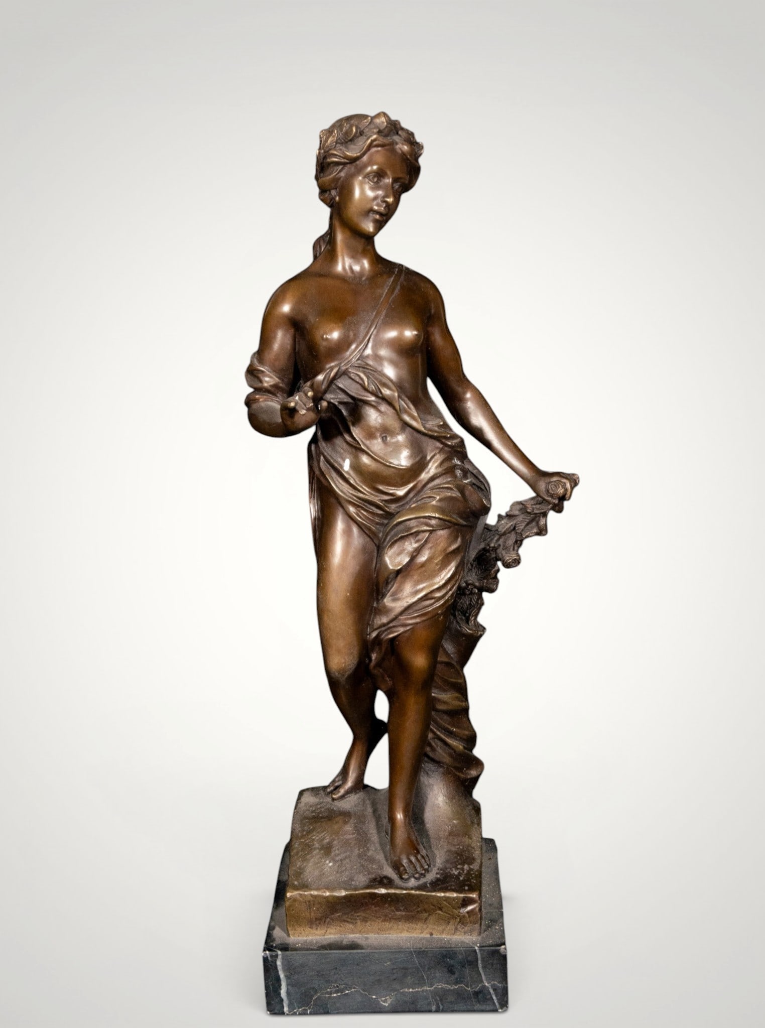 Female allegory. European School. 19th Century: Patinated bronze on a marble base. Measures 47 x 15 x 13 cm. Semi-nude female figure standing, with a close-fitting drapery and a vegetal attribute in her hand. The sinuous pose, the anatomical modeli