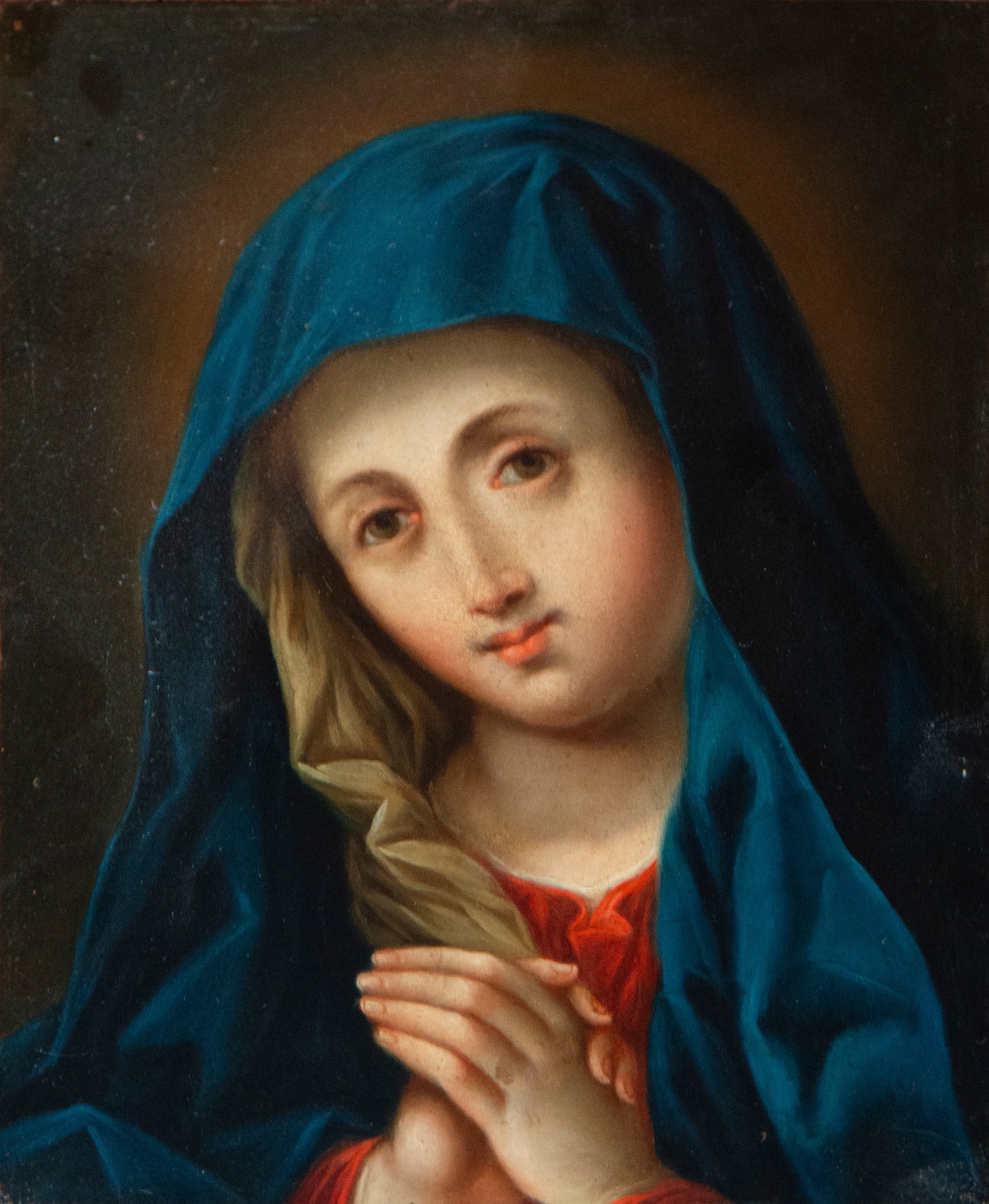 Virgin in prayer. Spanish school. 18th century: Oil on copper. Measures 24 × 18 cm. Small oval devotional painting depicting the Virgin Mary seated in a meditative pose, her hands clasped in her lap. A flowing blue mantle envelops the figure, whil