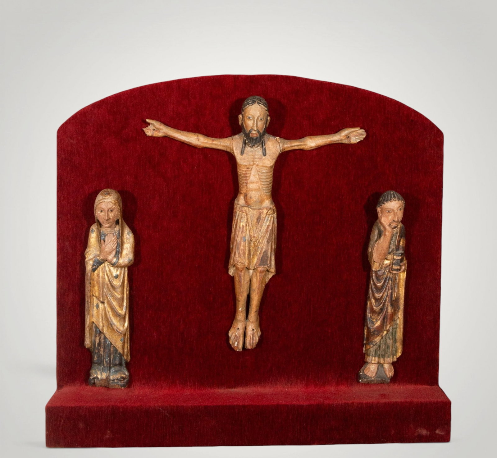 Calvary with the Virgin Mary and Saint John. Spanish Medieval School - 14th Century: Carved, polychromed, and partially gilded wood, with some repainting and restorations. Dimensions: 51 x 12 cm - 65 x 57 cm. Devotional group composed of Christ crucified, the Virgin Mary, and Saint Jo
