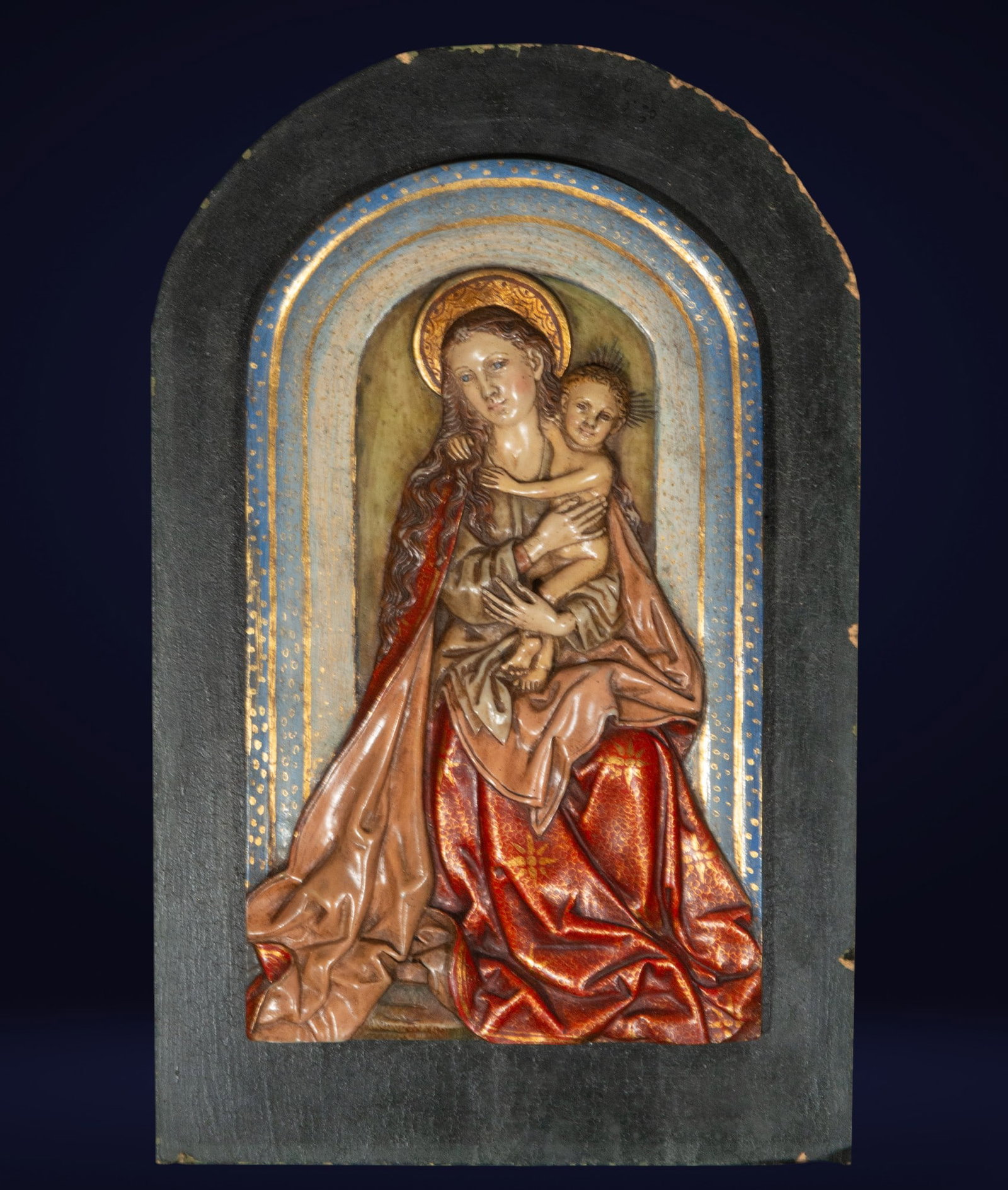 Alabaster relief of the Virgin and Child. Neo-Gothic School. 19th century: Polychrome alabaster on a wooden background. This delicate sculptural composition depicts the Virgin Mary in a serene attitude, tenderly holding the Child Jesus. The relief stands out for its brillian