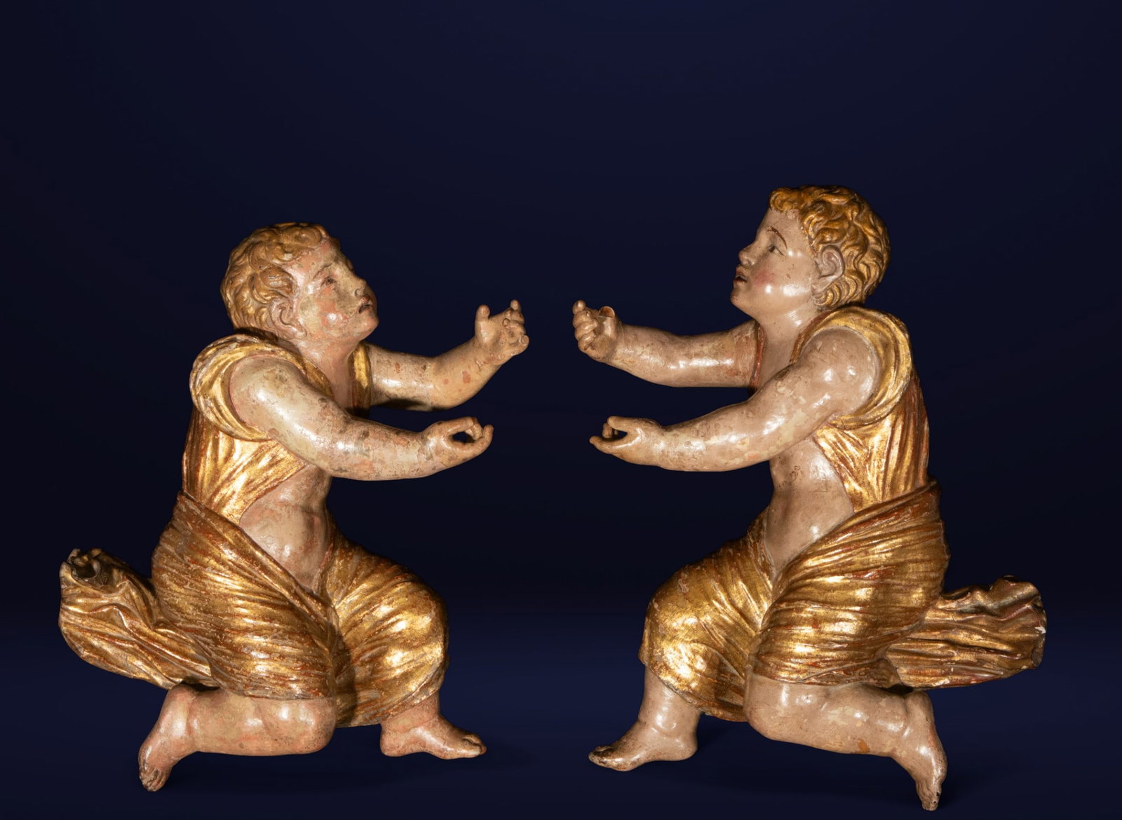Pair of praying angels - JUAN DE JUNI OR HIS WORKSHOP - Castilian School, Valladolid. 16th Century: Carved, polychromed, and gilded wood. Dimensions: 49 x 33 x 13 cm each. Devotional sculpture depicting two kneeling child angels with outstretched arms, seemingly holding or venerating a lost sacred o