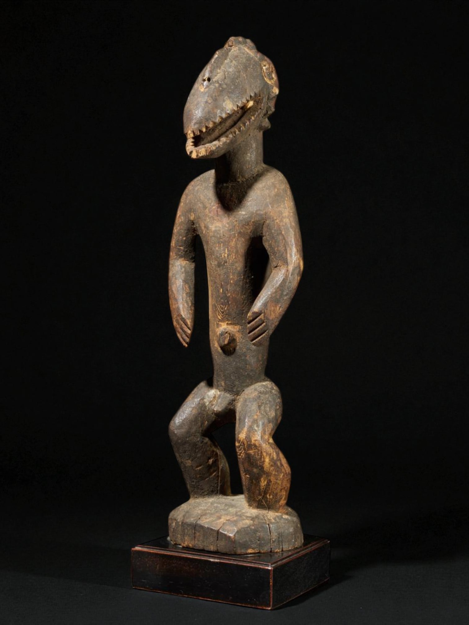 Montol-Goemai sculpture with Gugwom-type mask, Nigeria, first half of the 20th century: Wood and organic material. Dimensions: 42 × 13 × 12 cm. Ritual sculpture from the Montol-Goemai people depicting a male figure wearing a Gugwom mask, used in religious ceremonies and initiation danc