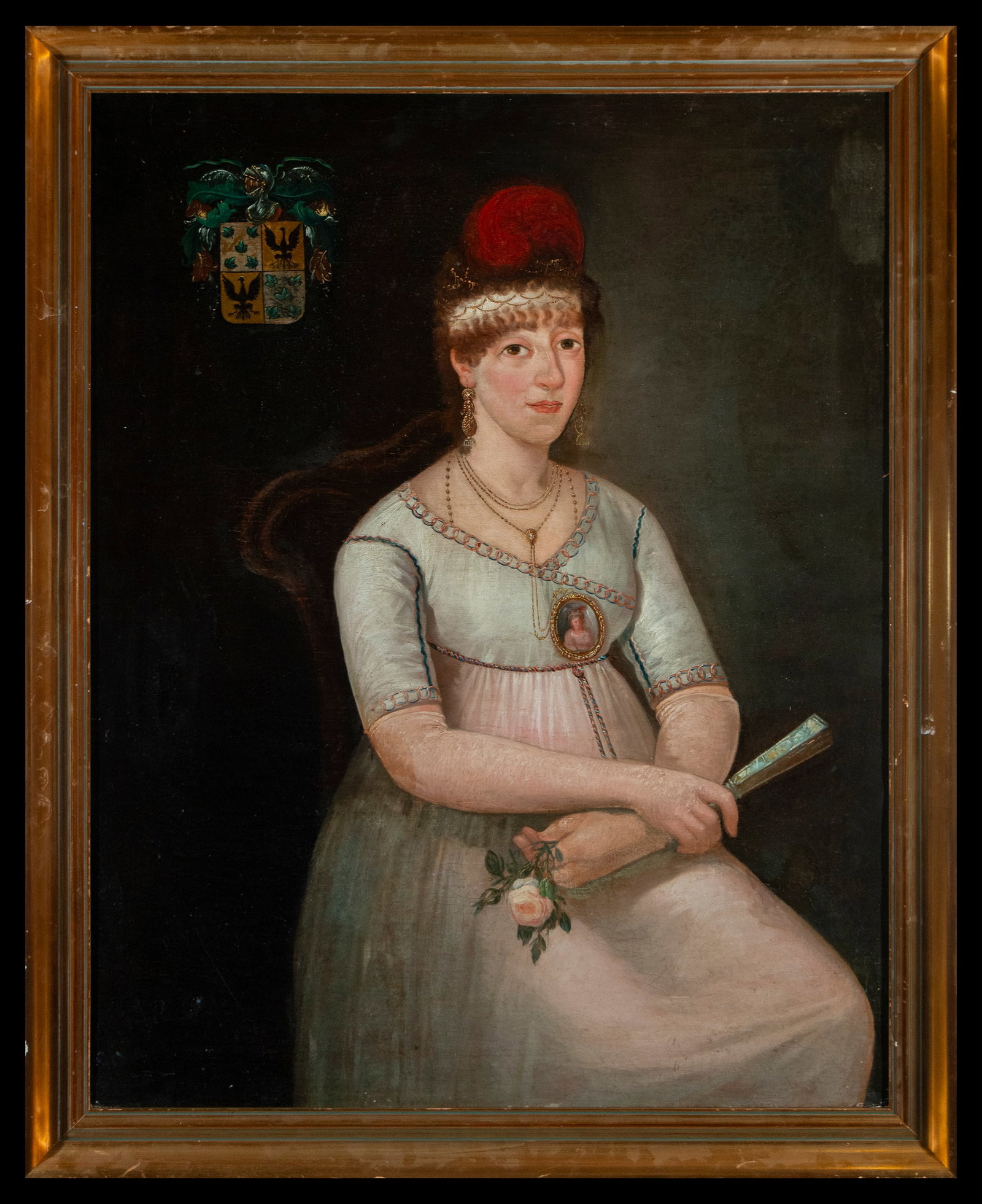 Colonial School of the 18th - 19th century, oil on canvas, dimensions: 114 x 92 cm: Portrait of an aristocratic lady in a distinguished attitude, with a serene expression and a fan in her hand. The family crest that adorns the background and the miniature on her chest highlight her l