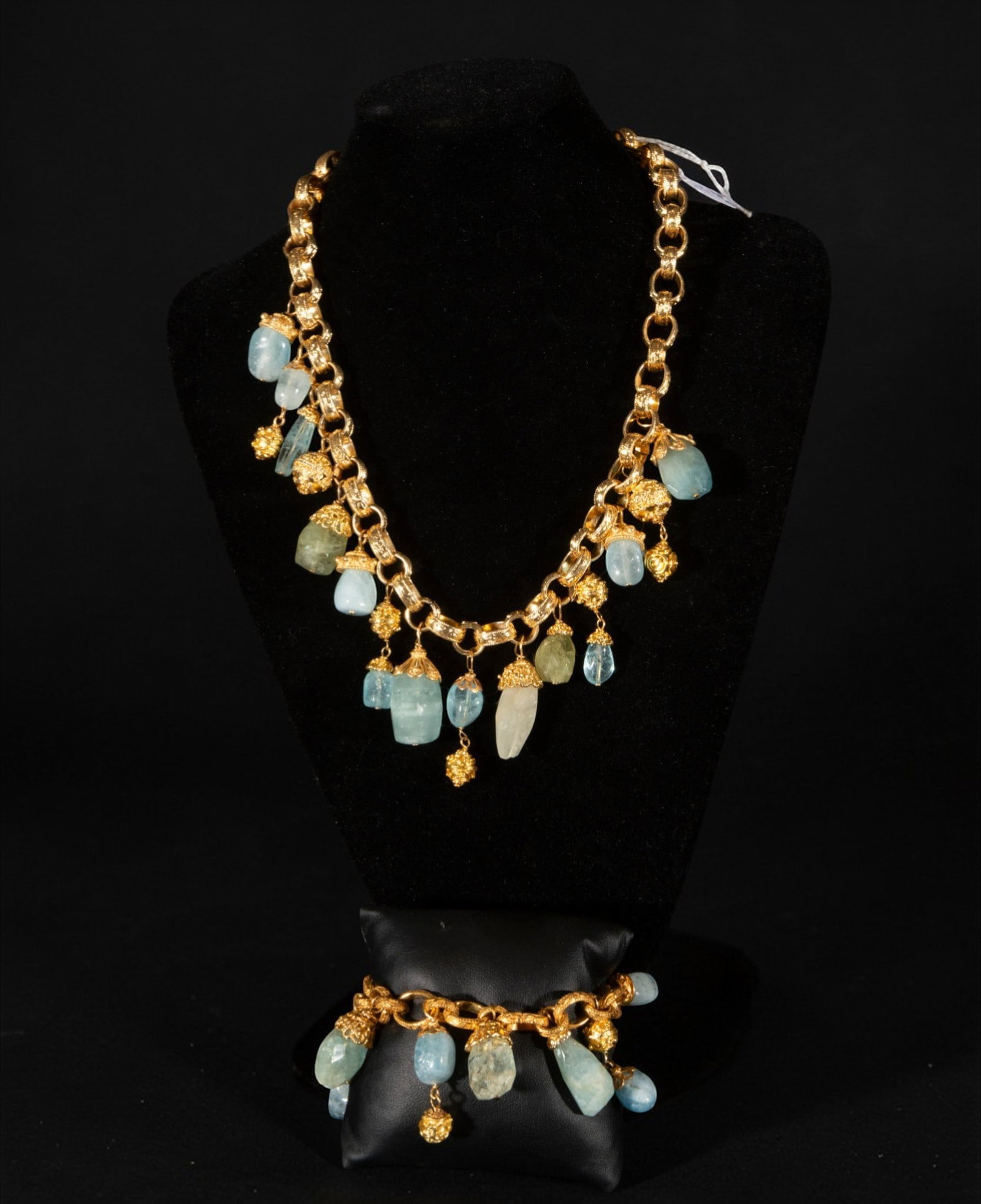 Gold-plated silver necklace with charms and chalcedony: Gold-plated silver necklace with charms and chalcedony. It features a large link chain from which hang multiple chalcedony pendants in shades of blue and green, combined with textured, gold-plated sph