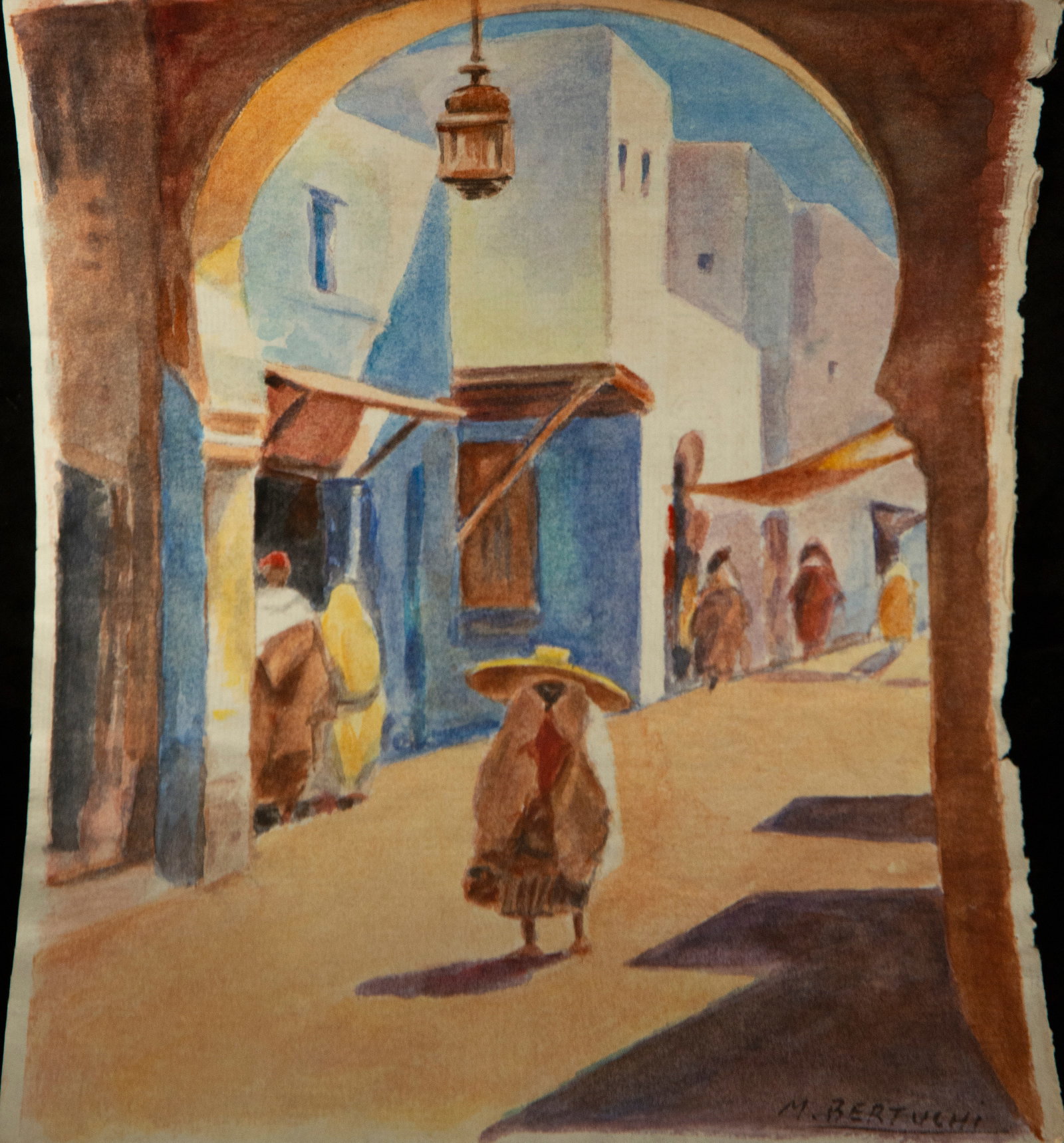 Urban scene Signed M. Bertuchi Orientalist School 20th Century: Watercolor on paper. The composition reveals a bright street with North African architecture, framed by a wide arch that creates an effect of stagecraft. Anonymous figures covered in djellabas move al