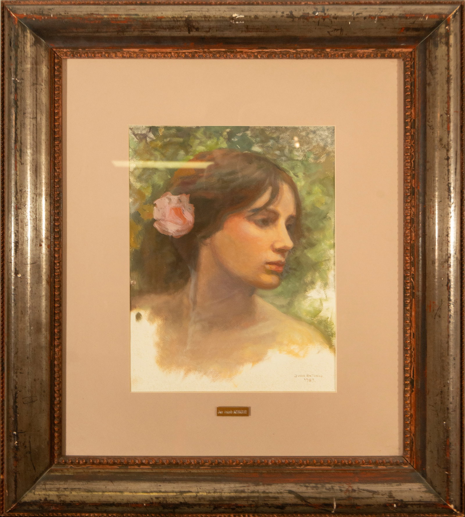 Female Portrait. Signed Juan Antonio Rodríguez Hernández. Spanish School. 20th Century: Pastel on paper. Dimensions: 43 x 32 cm. The work presents a delicate three-quarter portrait of a young woman, her hair tied back and a pink flower on her temple, against a diffuse green background. T