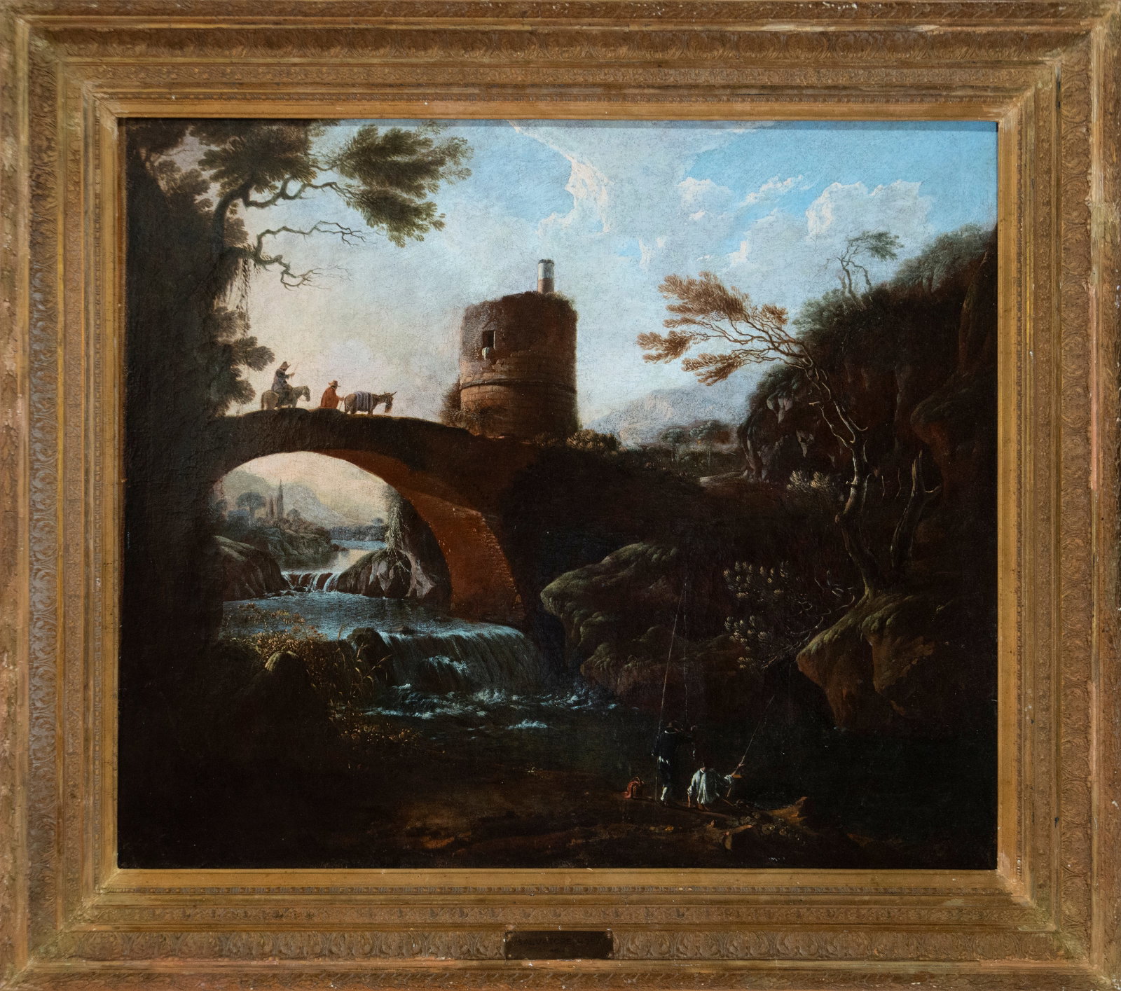 River landscape with bridge and tower, Italian School, 18th century: Oil on canvas. Dimensions 111 x 95 / 139 x 119 cm. An idealized landscape structured around a single-arched bridge crowned by a cylindrical tower, with a waterfall in the foreground, figures of travel