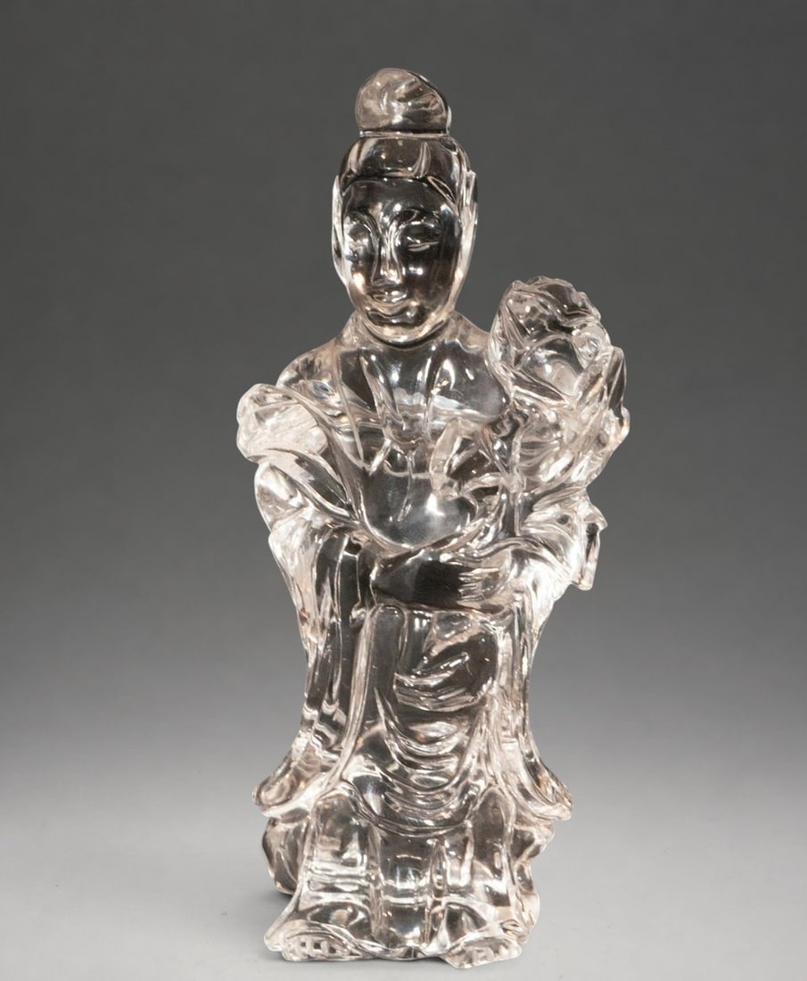 Guanyin figurine in rock crystal. Chinese School. 20th century: Carved rock crystal. Measures 15 x 7 x 5 cm. Sculpture depicting Guanyin, the bodhisattva of compassion, seated serenely amidst flowing folds. The transparency of the material and the fineness of the 