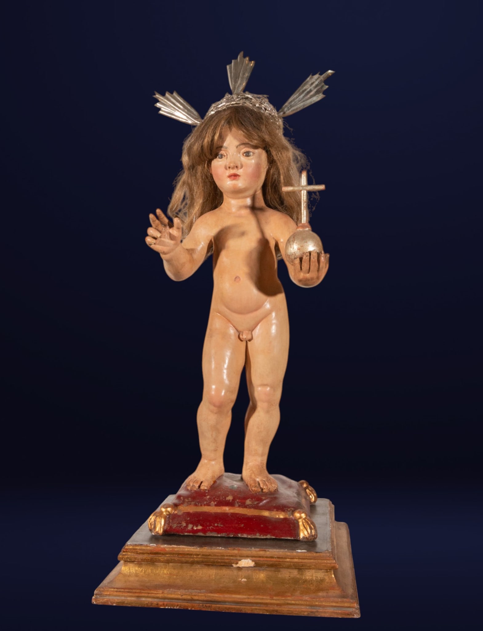 Child Jesus Savior of the World with silver rays, Spanish School, 17th Century: Polychrome sculpture with silver rays. Measures 71 x 26 x 22 cm and 80 x 35 x 31 cm. Child figure standing on a pedestal, nude, with a natural wig and halo of rays, blessing with the right hand and ho