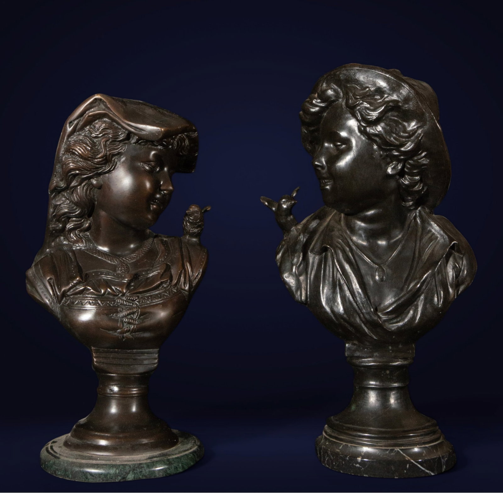Pair of French Bronze Busts, 19th Century: Pair of bronzes. Measures 44 x 24 x 19 cm. The set consists of two facing child busts, each mounted on a circular stand and stone base. The figures display rounded, expressive faces, wavy hair, and so