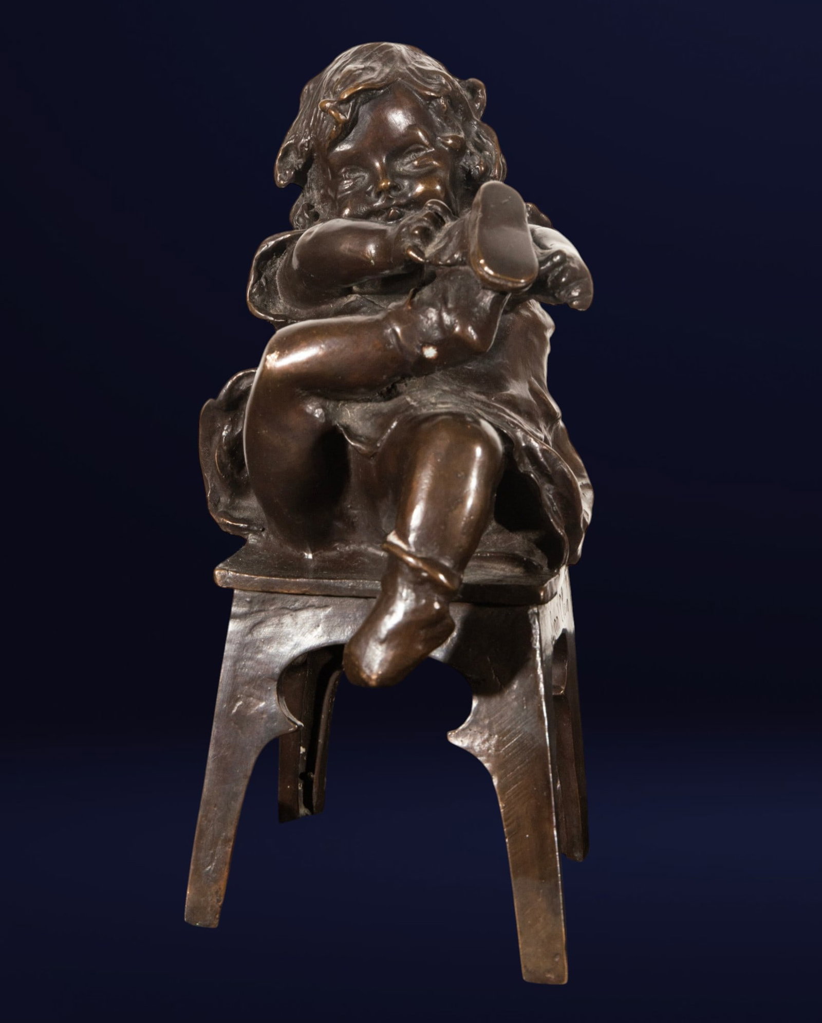 Girl sitting in chair, SIGNED JOAN CLARA: Bronze. Measures 22 x 10 x 12 cm. Small child figure seated on a low-backed chair, with one leg crossed over the other and arms gathered around the body in a self-absorbed attitude, showing loose hair