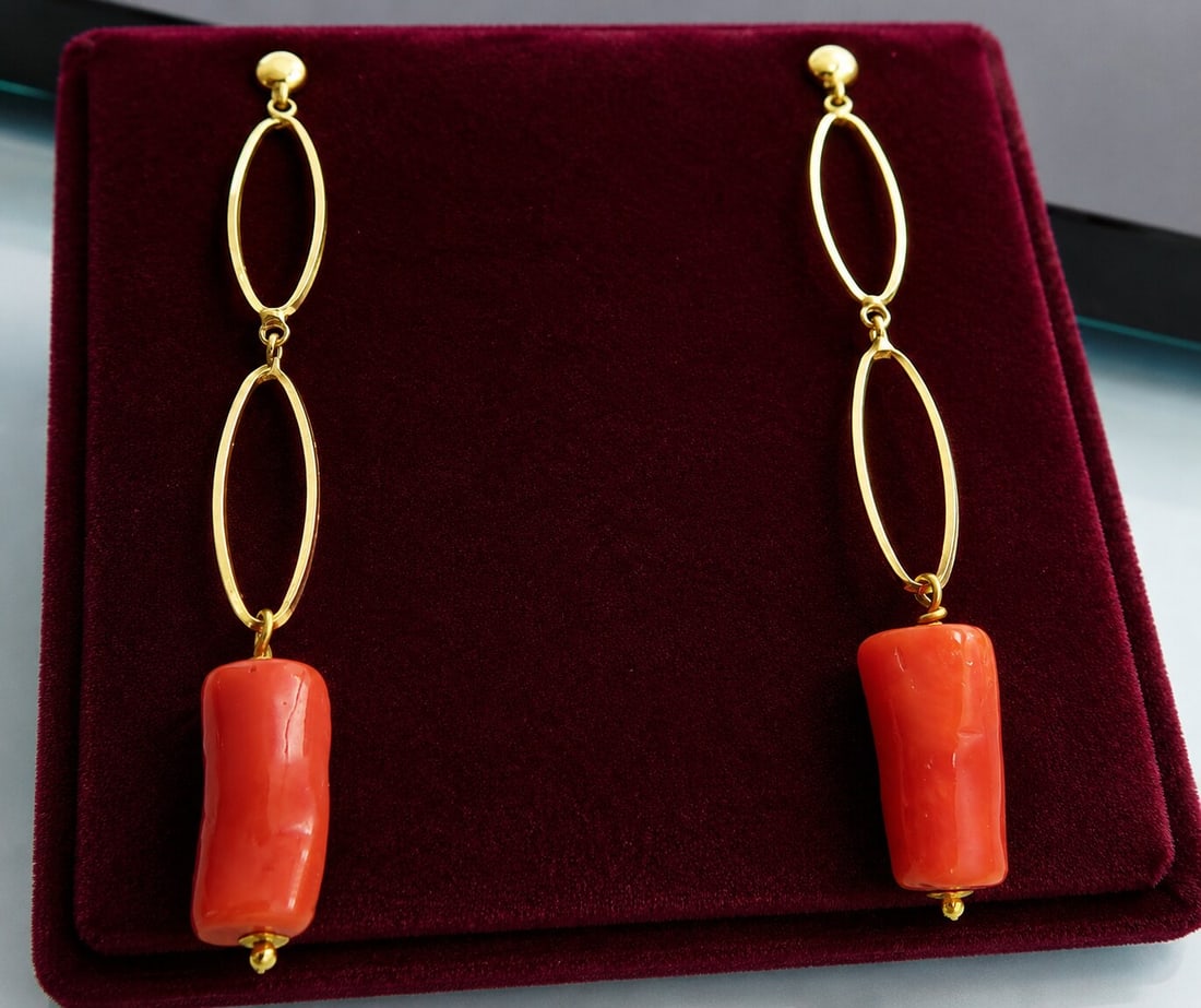 Long earrings with natural Mediterranean coral. 18-karat gold. Weight 4.1 grams: 18-karat yellow gold and natural Mediterranean coral. Measures 6.1 cm in length; corals 16 x 7 mm. Weight 4.1 grams. Pair of long, articulated earrings with two open, oval-shaped links, each topped wi