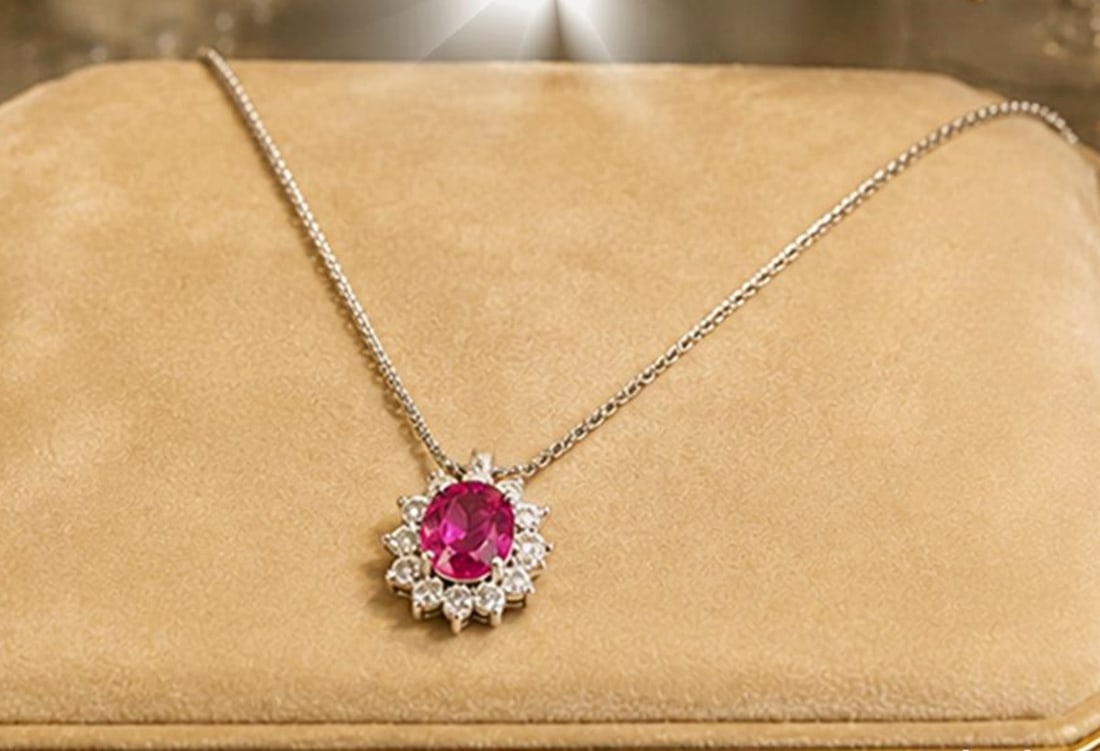 Necklace with ruby and 10 diamonds. 18-karat white gold. Weight 2.55 grams: Solid 18-karat white gold, oval-cut natural ruby, and ten brilliant-cut diamonds. Chain length: 42 cm; rosette: 9 mm. Weight: 2.55 grams. This fine jewelry necklace features a delicate chain and a ros