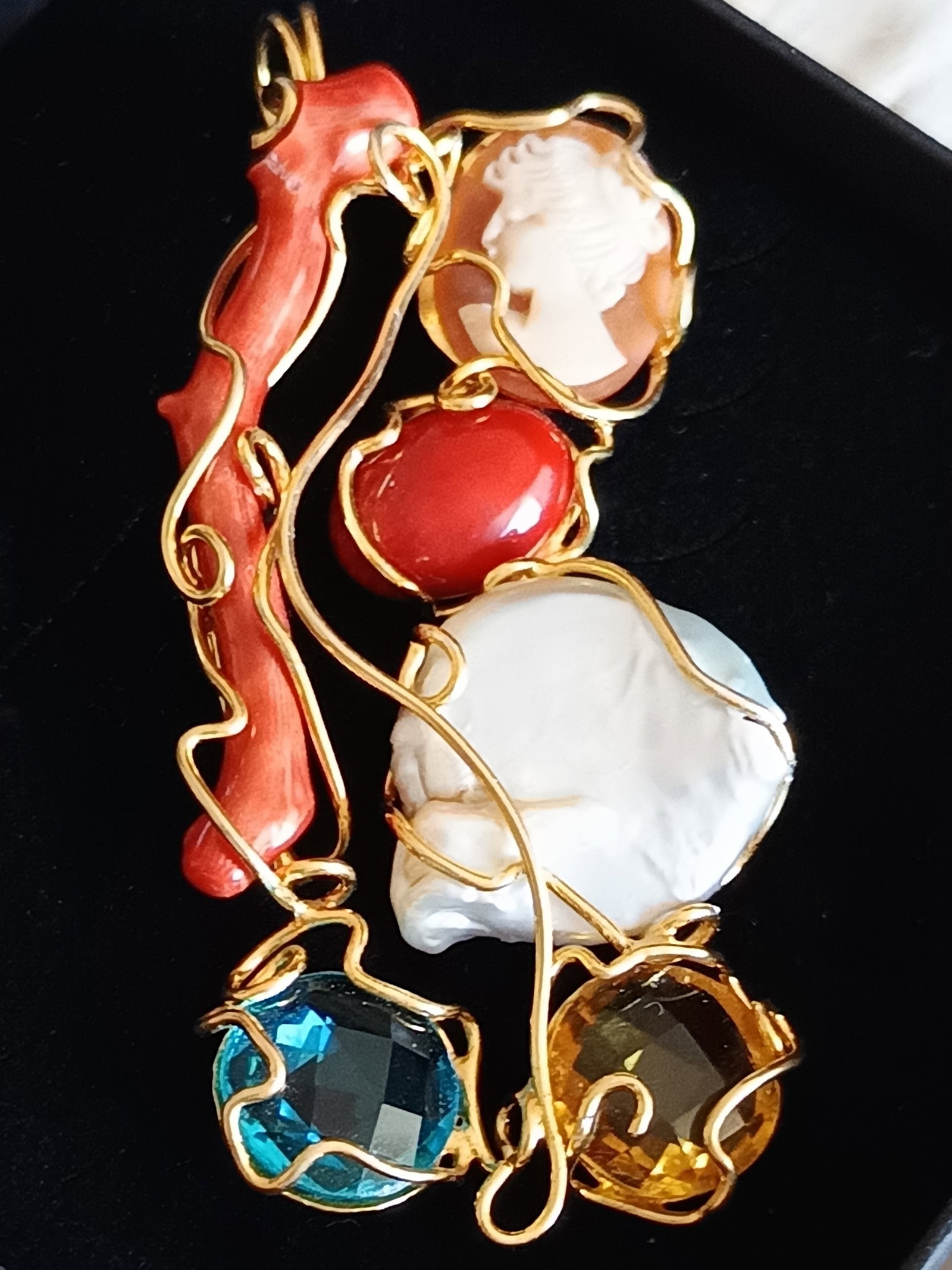Pendant with coral, cameo, pearl, and topaz. Sterling silver with gold plating. Weight: 15 grams: Silver with gold plating, worked with wrapped wire, natural Mediterranean coral, carved shell, baroque pearl, blue topaz, and citrine topaz. Measures 7.1 x 3.2 cm; coral branch 4.8 cm; coral cabochon 