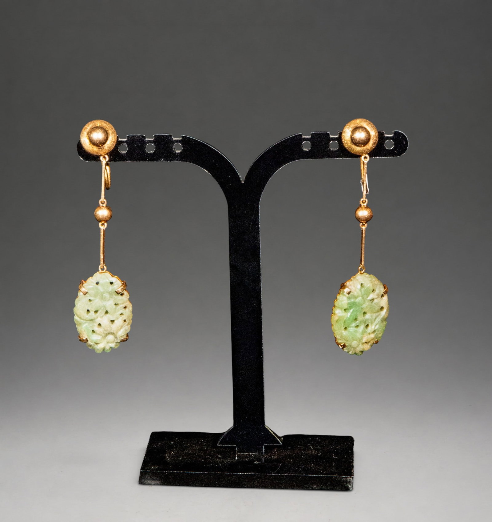 18K gold earrings with jade, 1920s. 9.87g: 9.87g. Pair of earrings made of 18K gold with carved jade pendants. The design consists of a spherical upper section attached by an articulated link to the main motif, which is made up of oval-shaped 