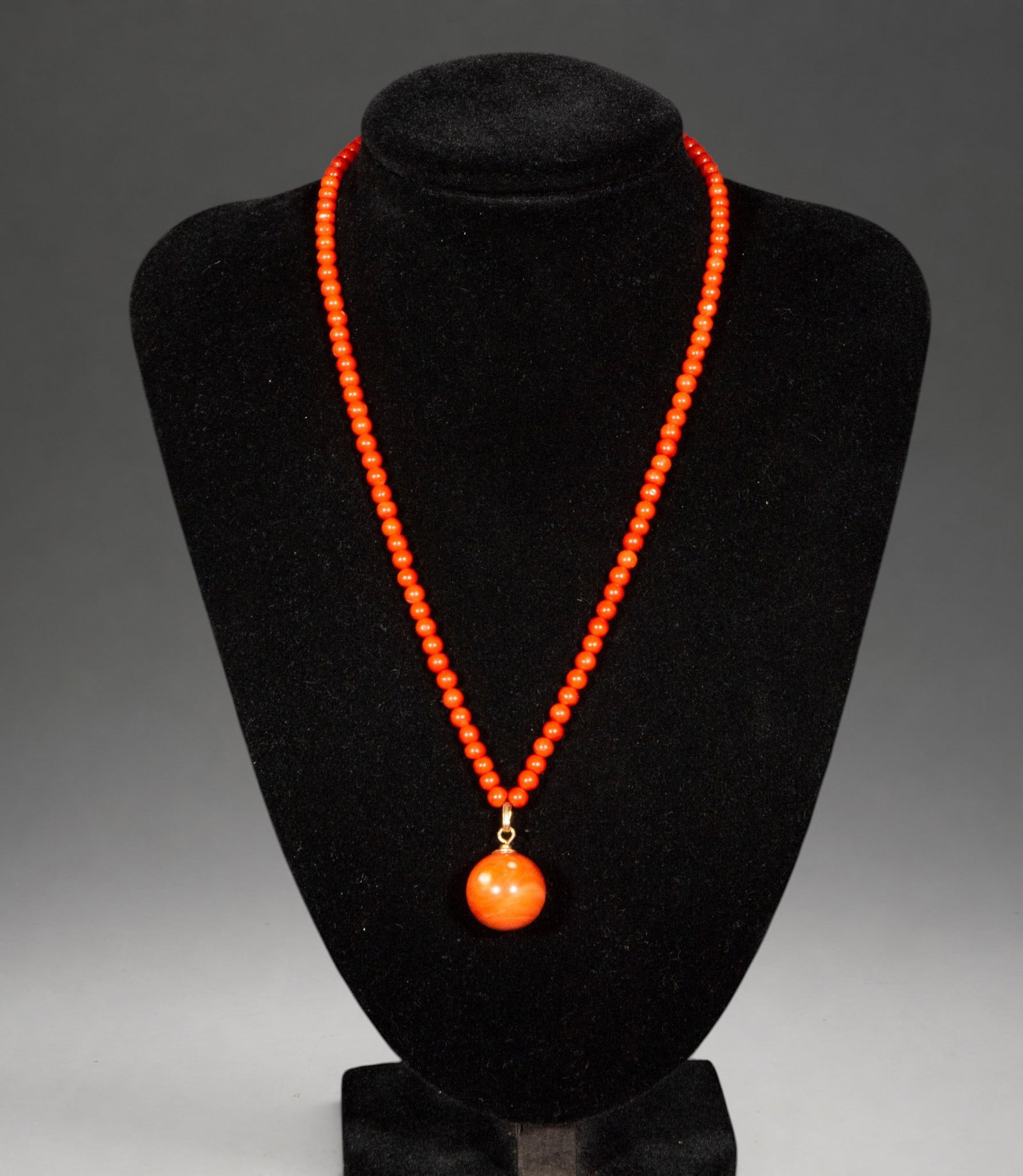 Coral bead necklace with silver clasp and antique coral ball pendant: Necklace made with small natural coral beads, culminating in a pendant with a larger antique coral bead. It features a silver clasp and a simple design that highlights the beauty and intense color of 
