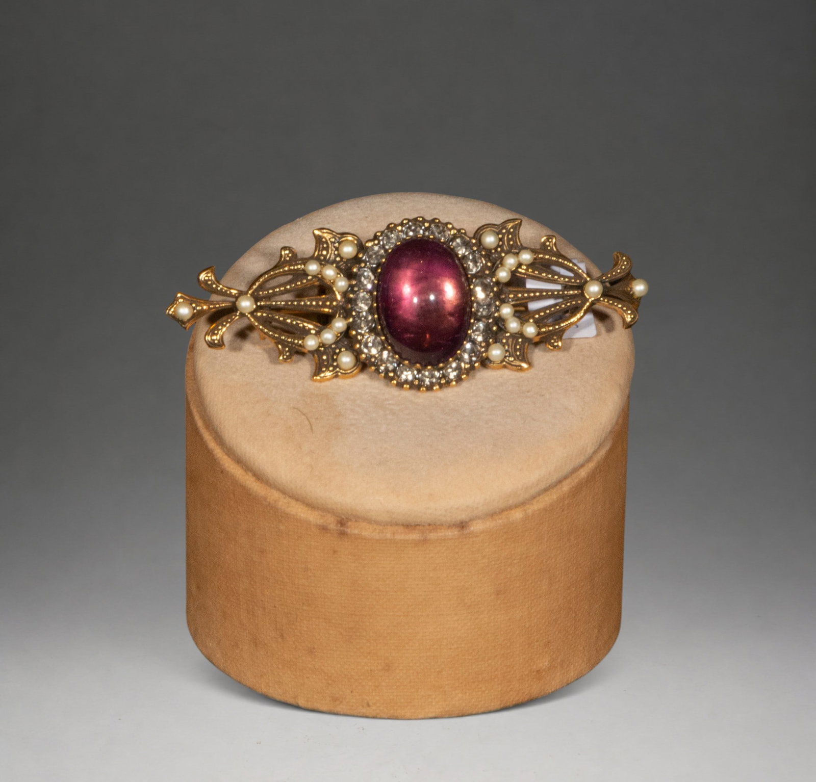 Gold-plated silver brooch with pearls, amethyst and cubic zirconia: A silver-gilt brooch featuring a cabochon-cut amethyst as its central motif, surrounded by cubic zirconia and natural pearls. The side arms showcase a 19th-century-inspired floral design that adds ele