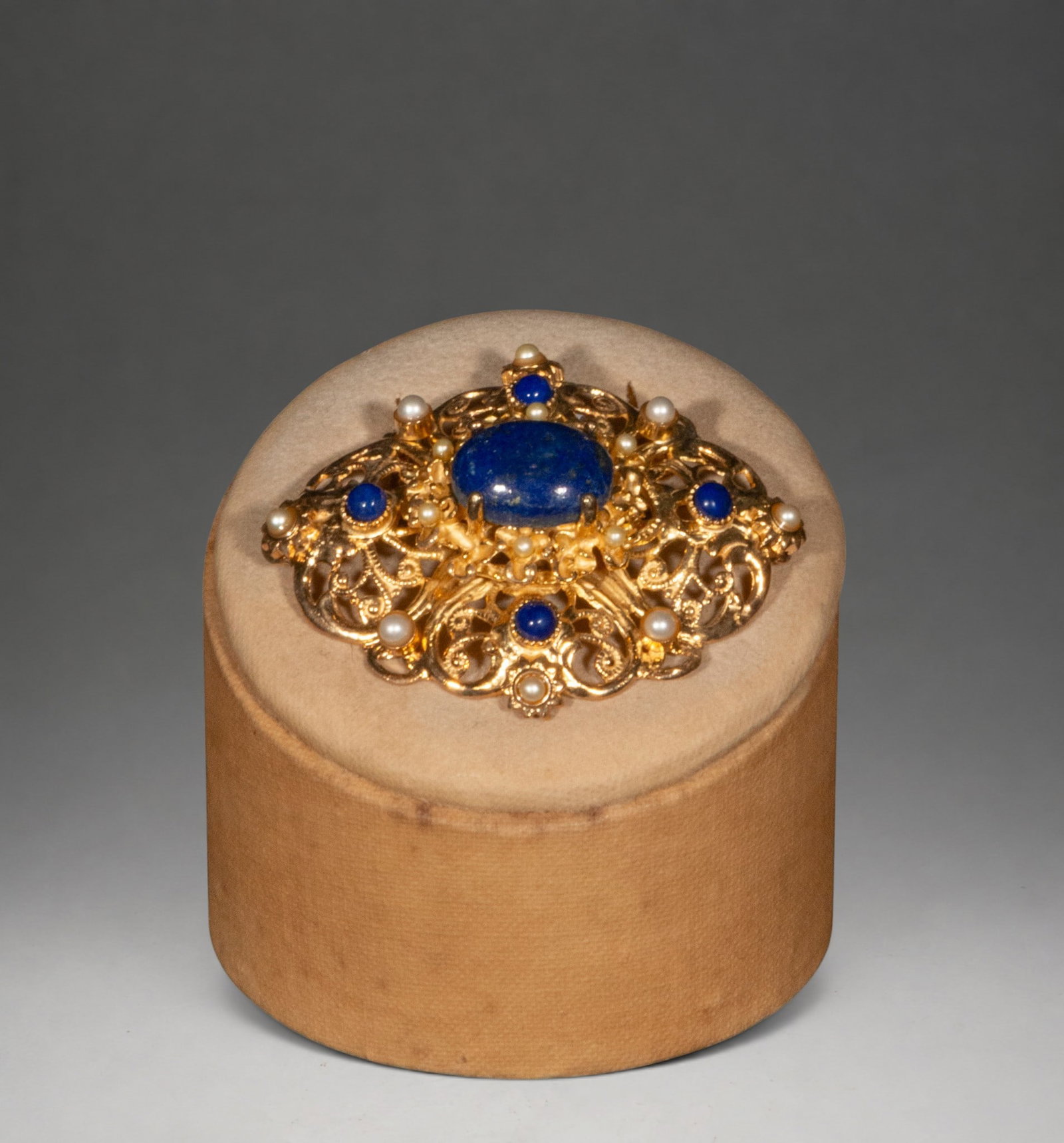 Gilded silver brooch with lapis lazuli and pearls: Gilded silver brooch with a large central cabochon of lapis lazuli, accompanied by smaller cabochons of the same material and pearls. Its openwork and symmetrical structure is reminiscent of historici