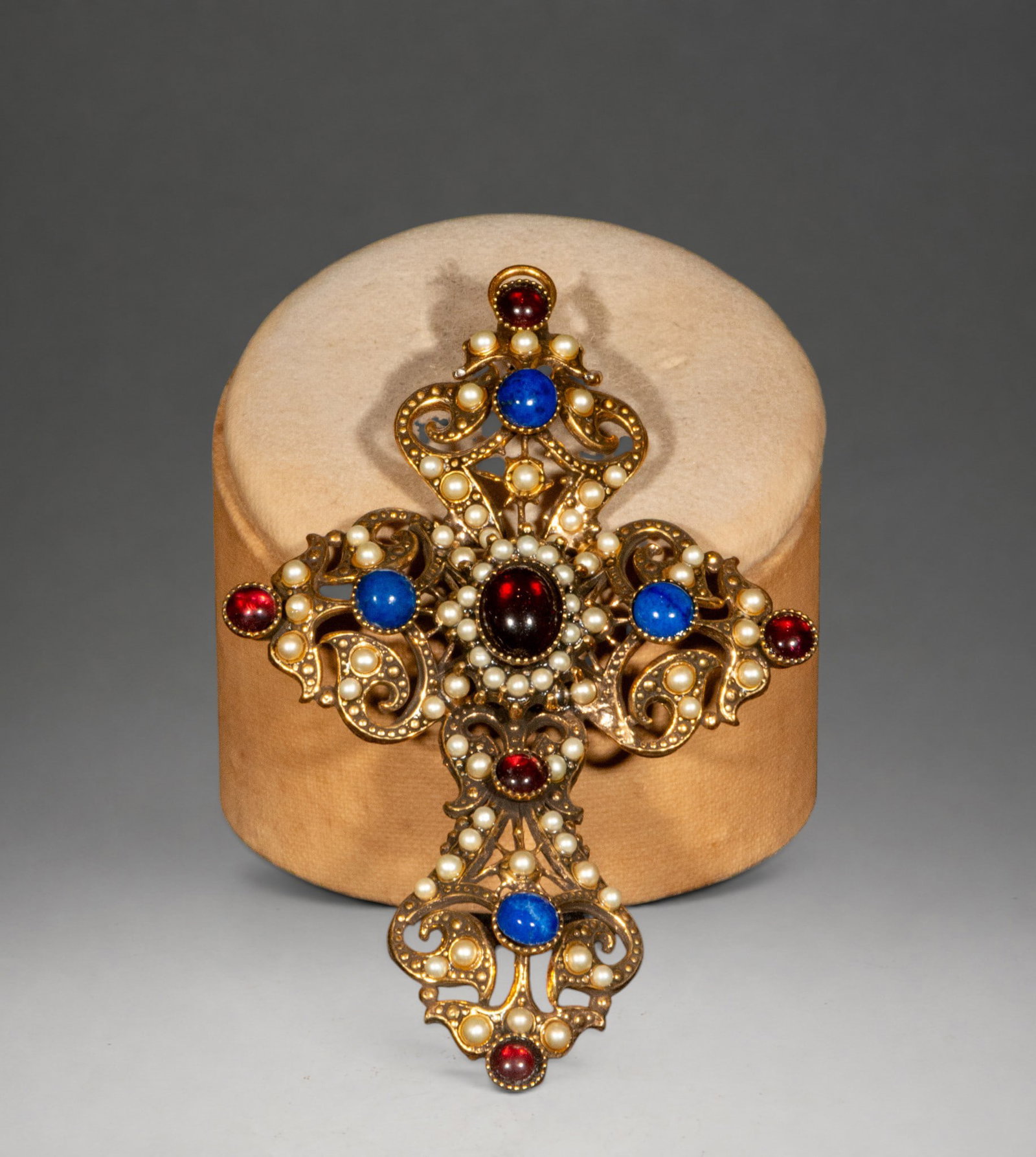 Gilded silver cross with lapis lazuli, garnets and pearls: A richly ornamented silver-gilt cross set with cabochons of lapis lazuli and garnets, framed by pearl appliqués. The elaborate openwork and symmetrical arrangement of the gems evoke historicist jewel