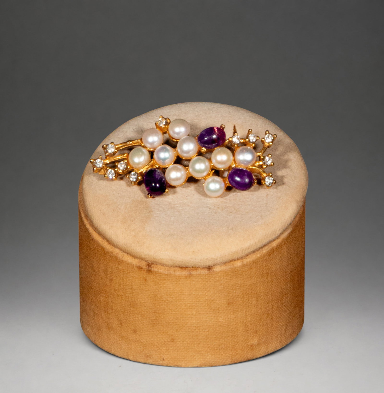 Silver-gilt brooch with pearls and amethyst: A silver-gilt brooch with a floral design, decorated with cultured pearls, amethyst cabochons, and cubic zirconia. The arrangement of the elements creates a delicate, naturalistic effect.