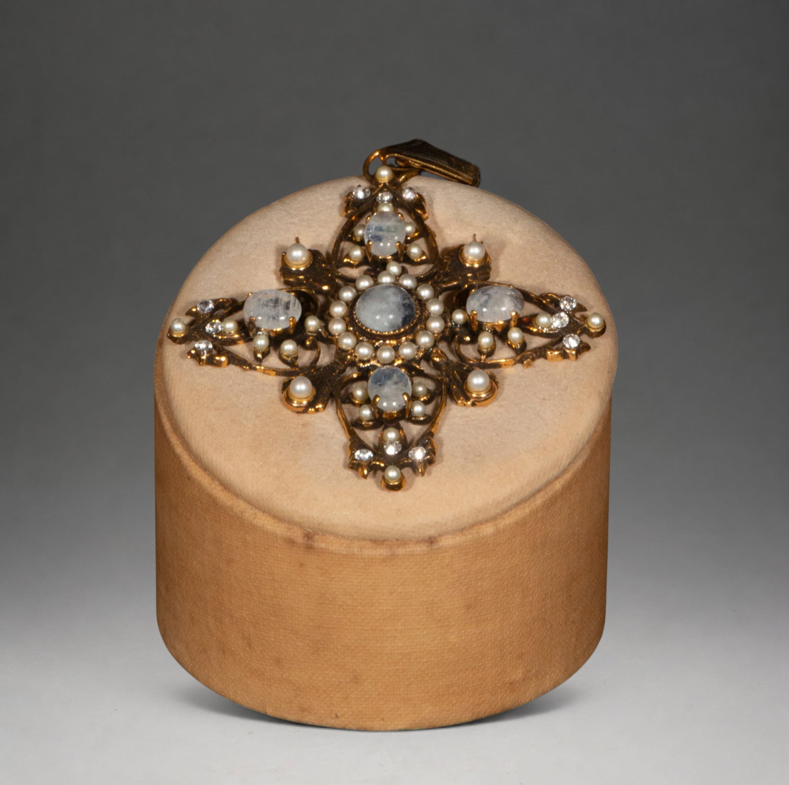 Gilded silver cross with moonstone: Silver-gilt cross with moonstone cabochons, pearls, and cubic zirconia. The openwork structure and iridescent sparkle of the stones enhance its refined ornamental character.