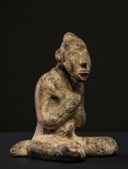 Seated female figure with arms crossed over her chest, Mali, 20th century: Cast copper alloy. MEASURES: 21 × 19 × 16 cm. Sculpture depicting a woman kneeling on her heels, with her arms crossed over her chest, a symbol of motherhood, fertility, and ancestral respect. This 