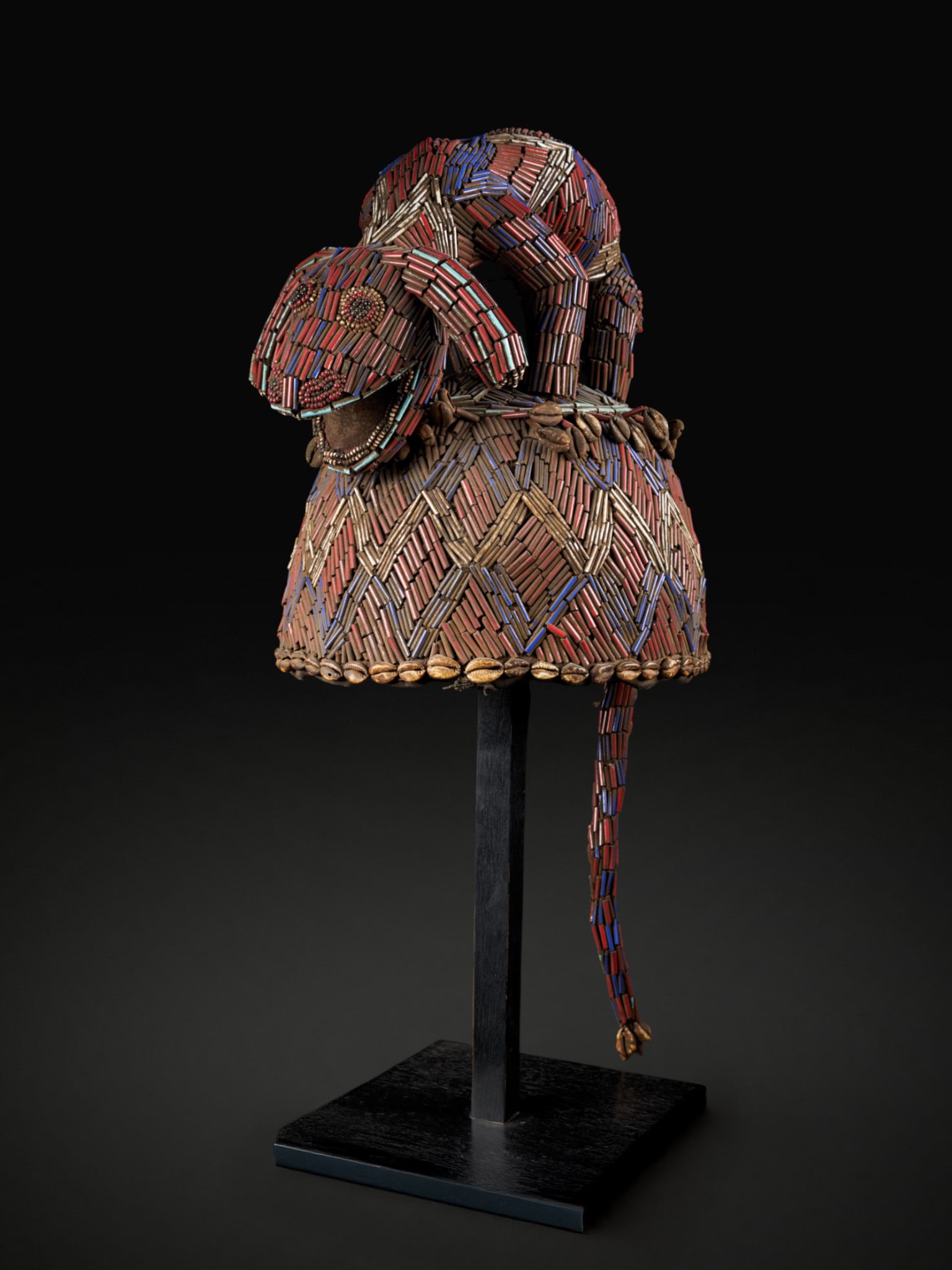 Ceremonial headdress with cowrie shells and tail. Grassland people, Cameroon: Glass beads and cowrie shells. Dimensions: 28 × 24 × 30 cm. Ceremonial headdress from the Grassland culture of Cameroon, richly decorated with contrasting colored glass beads and finished with a cow