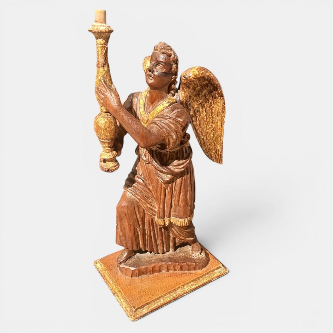 Angel torchbearer or candle holder in gilded wood, Venice, Italy, 17th century: Carved and gilded walnut. Dimensions: 52 cm high. This sculpture represents a candle-bearing angel, conceived as a support for liturgical lighting, a typology widely used in Venetian religious decorat