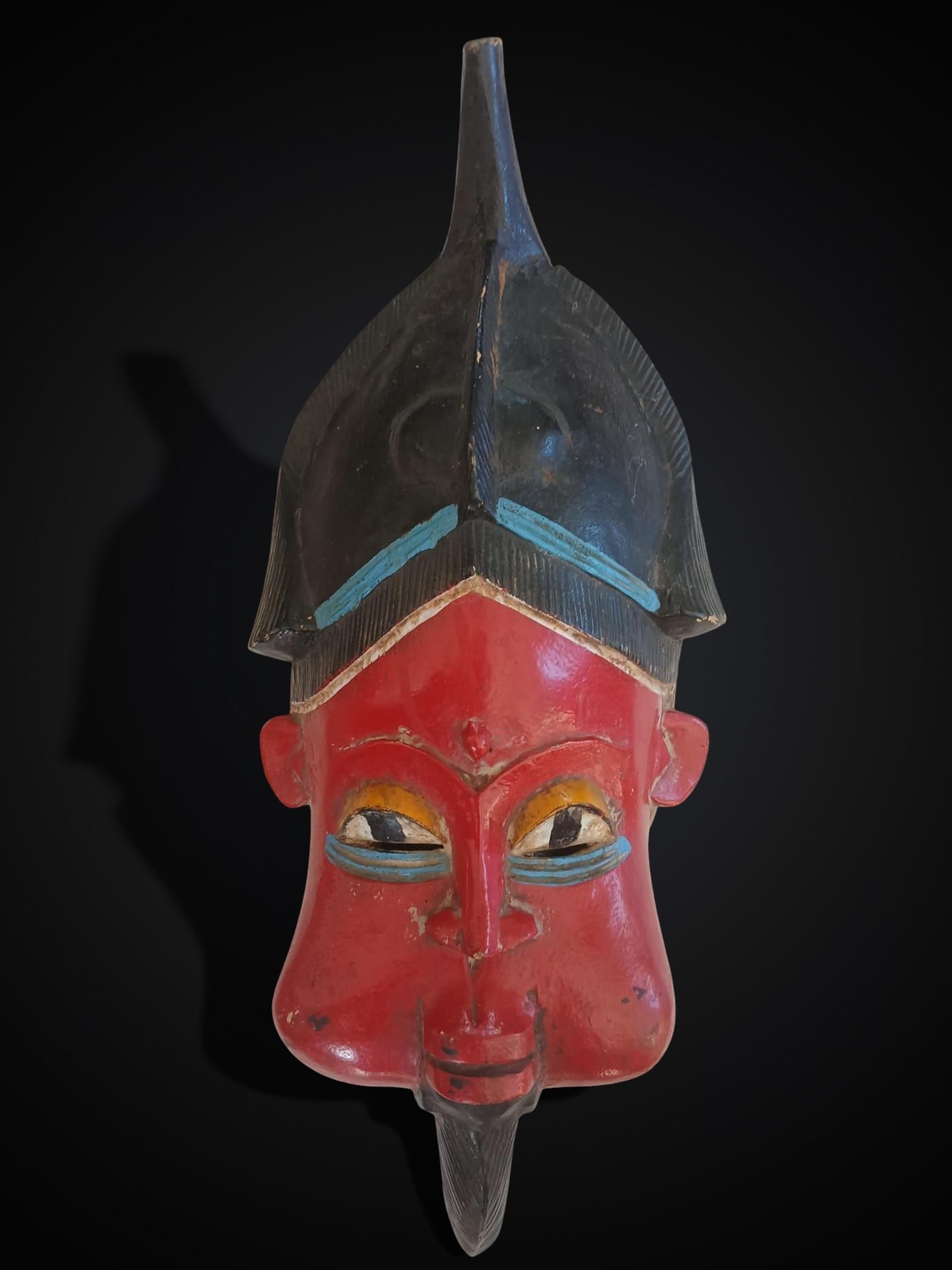 Polychrome ritual mask, Benin culture, 20th century: Carved and polychromed wood. African ritual mask belonging to the Benin culture, characterized by expressive carving and the use of traditional polychromy. Dimensions: 49 × 18 cm. Lot in internationa