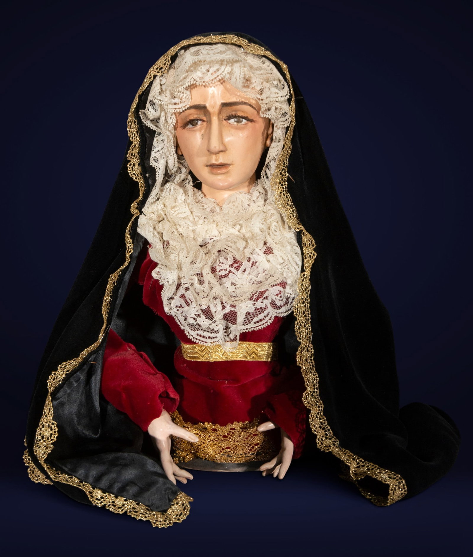 Sculpture of Our Lady of Sorrows in period clothing, Bolognese School, 19th Century: Polychrome terracotta and textiles. Dimensions: 35 x 27 x 21 cm. This devotional sculpture depicts Our Lady of Sorrows in bust form, with a sorrowful expression and a raised gaze charged with emotiona