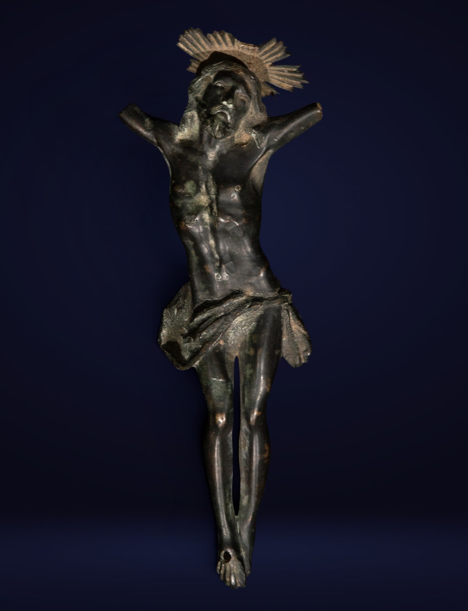 Christ in bronze, Spanish School, 18th Century: Cast bronze with a dark patina. Dimensions: 18 x 6 x 2.5 cm. Figure of Christ crucified with striking expressiveness, stylized anatomy, and a loincloth with soft folds. The piece retains an intense de