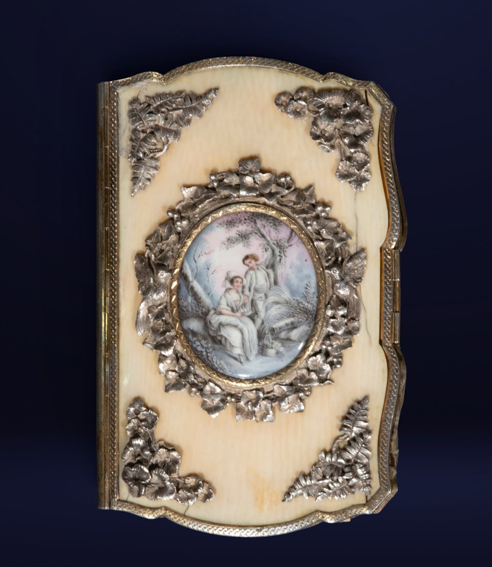 French dance booklet, French school, 19th century: Fine materials: sterling silver and painted porcelain. Dimensions: 11 x 7 x 1.5 cm. A refined French dance card with an elegant rectangular cut-out structure, decorated with raised floral appliqués a