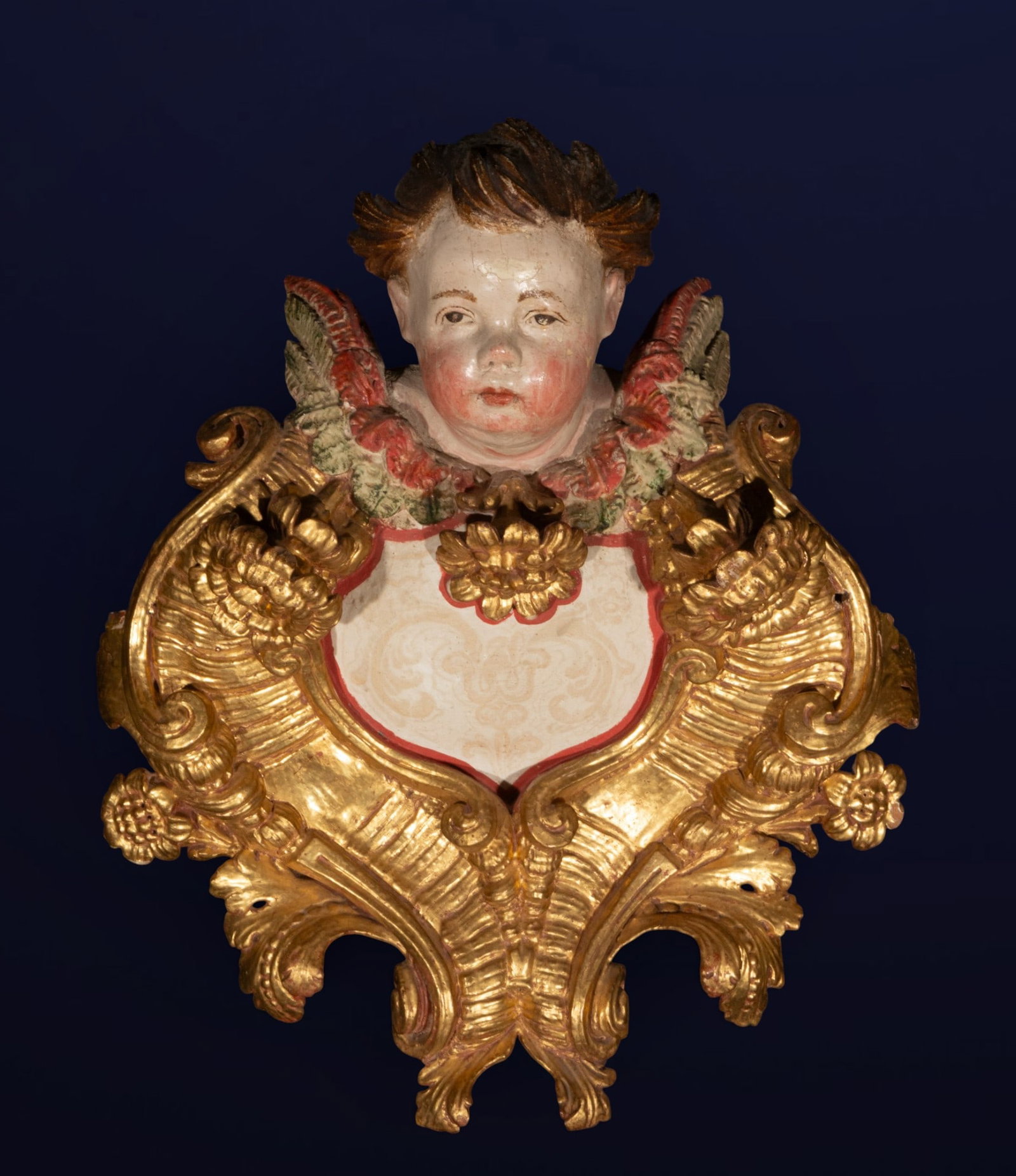 Altar finial with cherub, Spanish School, 17th Century: Carved, polychromed, and gilded wood. Ornamental altar finial composed of abundant gilded scrolls and vegetal motifs framing a central decorative shield crowned by a polychromed cherub's head. The com