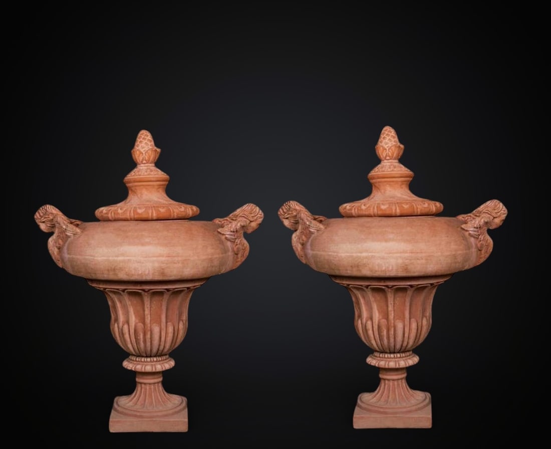 Pair of Agresti Vases with Angels. Italian School. 21st Century: Moulded terracotta. Dimensions 102 x 104 cm. Pair of ornamental vases crafted in Impruneta terracotta, remarkable for their commanding volume and artisanal finish. Each piece rises from a square-based