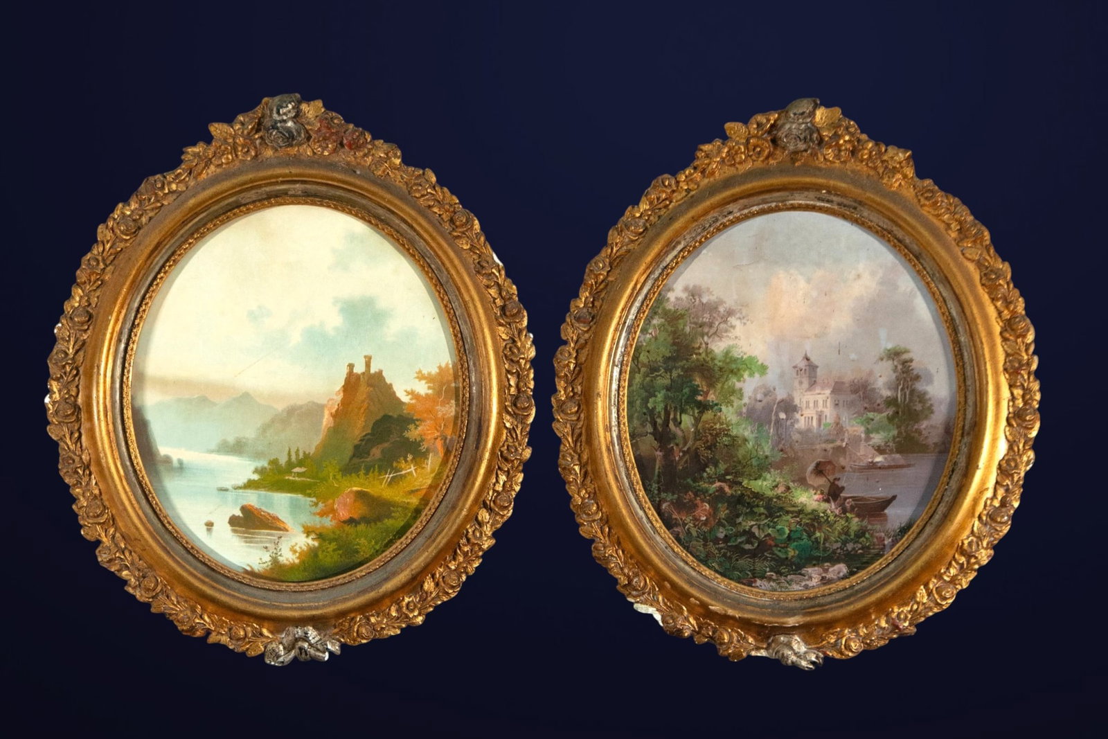 Pair of round frames with landscape prints, European School, 19th Century: Pair of round gilt frames with polychrome prints. Dimensions: 41 x 35 cm; with frame 60 x 50 cm. Decorative set composed of two oval landscapes framed in gilt moldings with abundant floral and rocaill