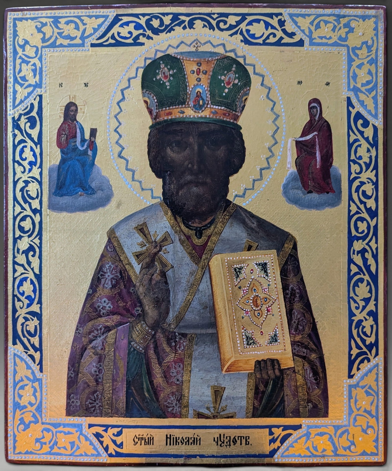 Icon of Saint Nicholas of Myra enthroned, Russian School, 19th Century: Tempera on cypress wood panel with ornately gilded background and border. Measures 35.2 x 30.3 cm. Icon with a frontal bust of Saint Nicholas of Myra, vested in episcopal robes and a jeweled crown, ho