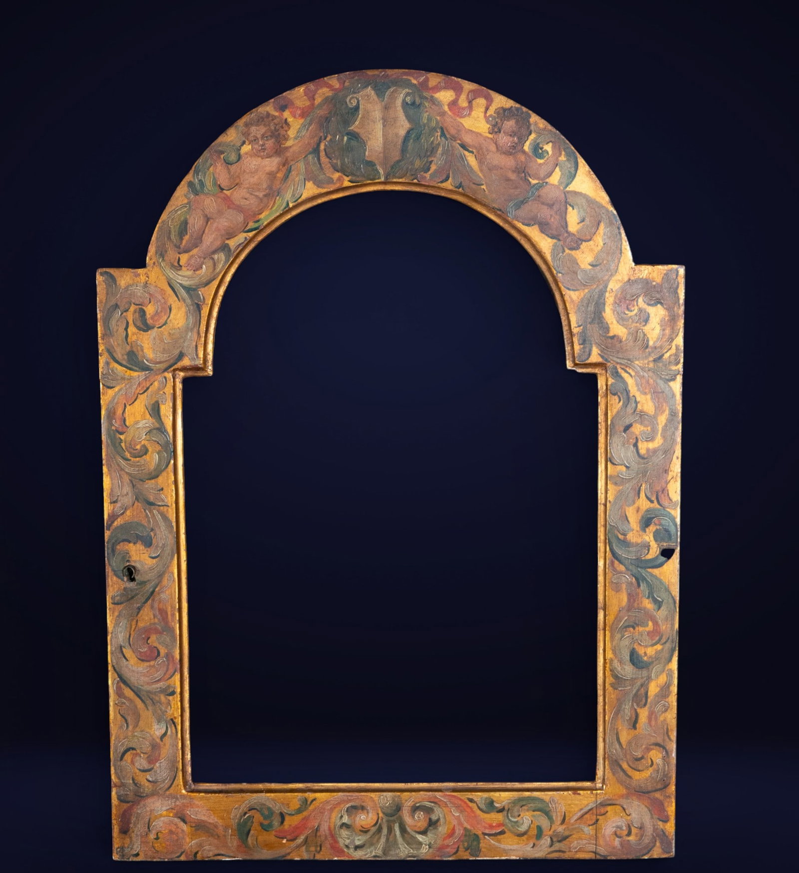 Frame with polychrome door, Spanish School, 18th Century: Carved and polychromed wood. Dimensions: 43 cm x 28 cm; 56 cm x 40 cm. Architectural frame with an arched finial and polychrome vegetal decoration in shades of green, ochre, and red on a gold backgrou