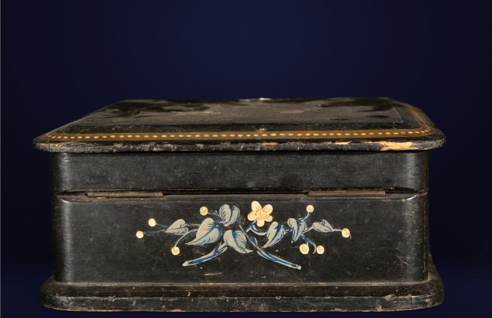 Painted box, European School, 19th century: Lacquered and painted wood. Dimensions: 8 cm x 19 cm x 19 cm. Rectangular box decorated with stylized floral motifs in shades of blue and gold on a black background. The composition stands out for the
