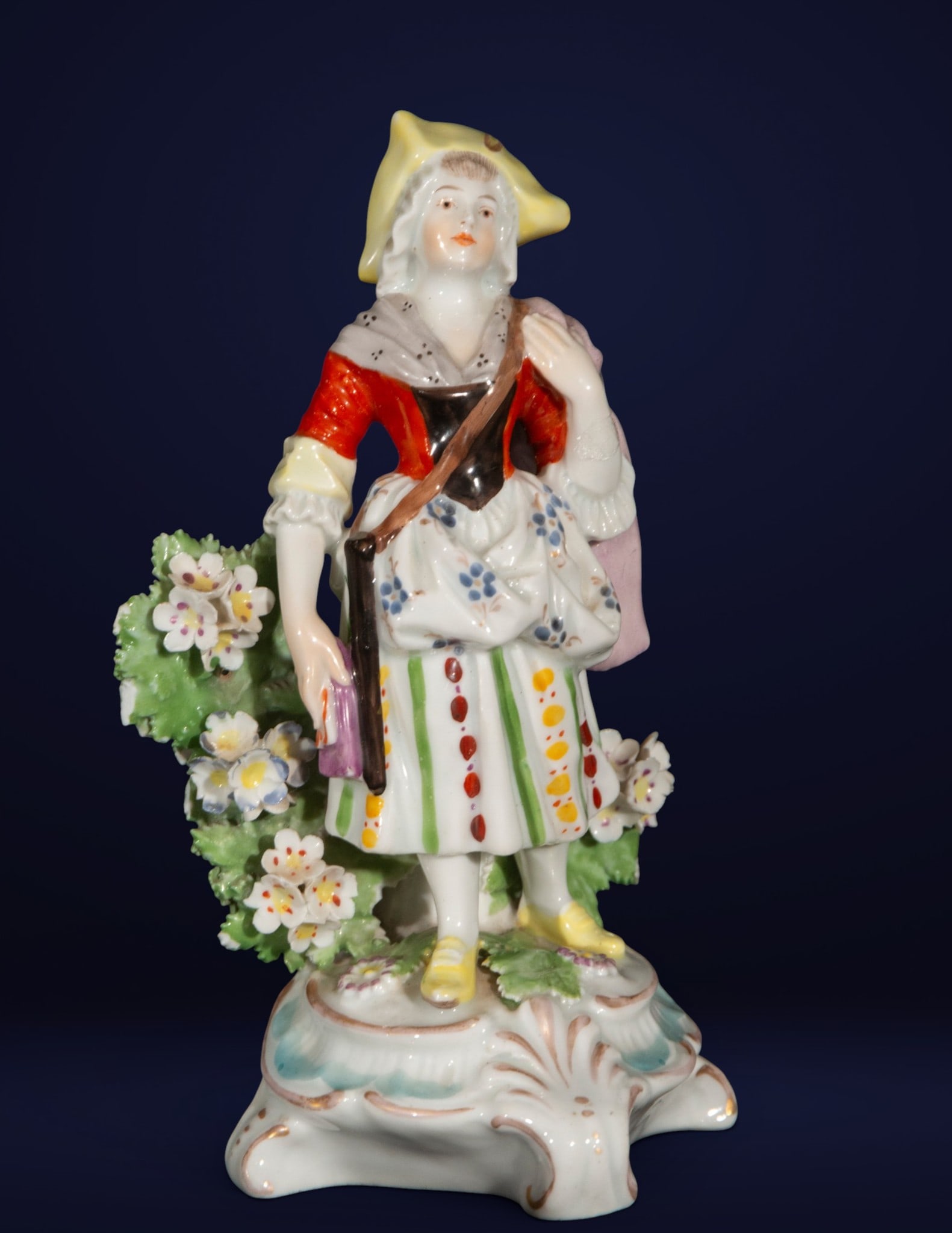 French porcelain figurine, French School, 20th century: Glazed and polychrome porcelain. Dimensions: 17 cm x 9 cm x 8 cm. Female figure in folk attire with floral decoration on a rocaille base, executed with vibrant colors and gilded details. The piece fol