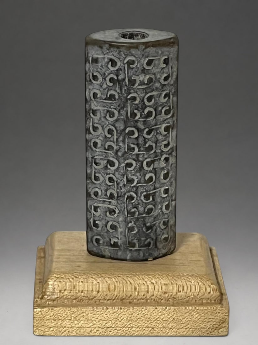 Ritual tubular pearl in jade, Zhanguo period, 5th-3rd century BC. c.: Carved and perforated jade. Measures 5.5 cm. Oval-sectioned tubular element decorated on all four sides with geometric relief patterns formed by archaic motifs of volutes and stylized hooks associated
