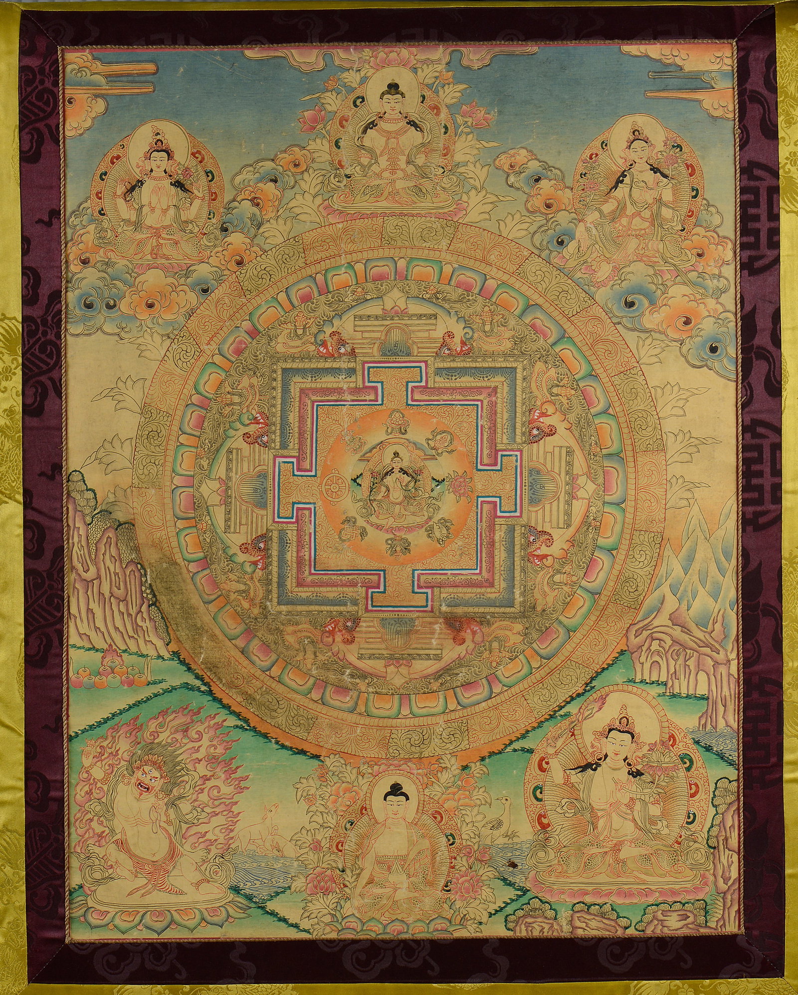 Exceptional Tibetan Thangka with mandala, 18th century: Polychrome pigments on silk with brocade. Dimensions: 64 x 47 cm; with brocade: 117 x 70 cm. The composition is centered on a circular mandala inscribed within a stepped geometric structure, surrounde