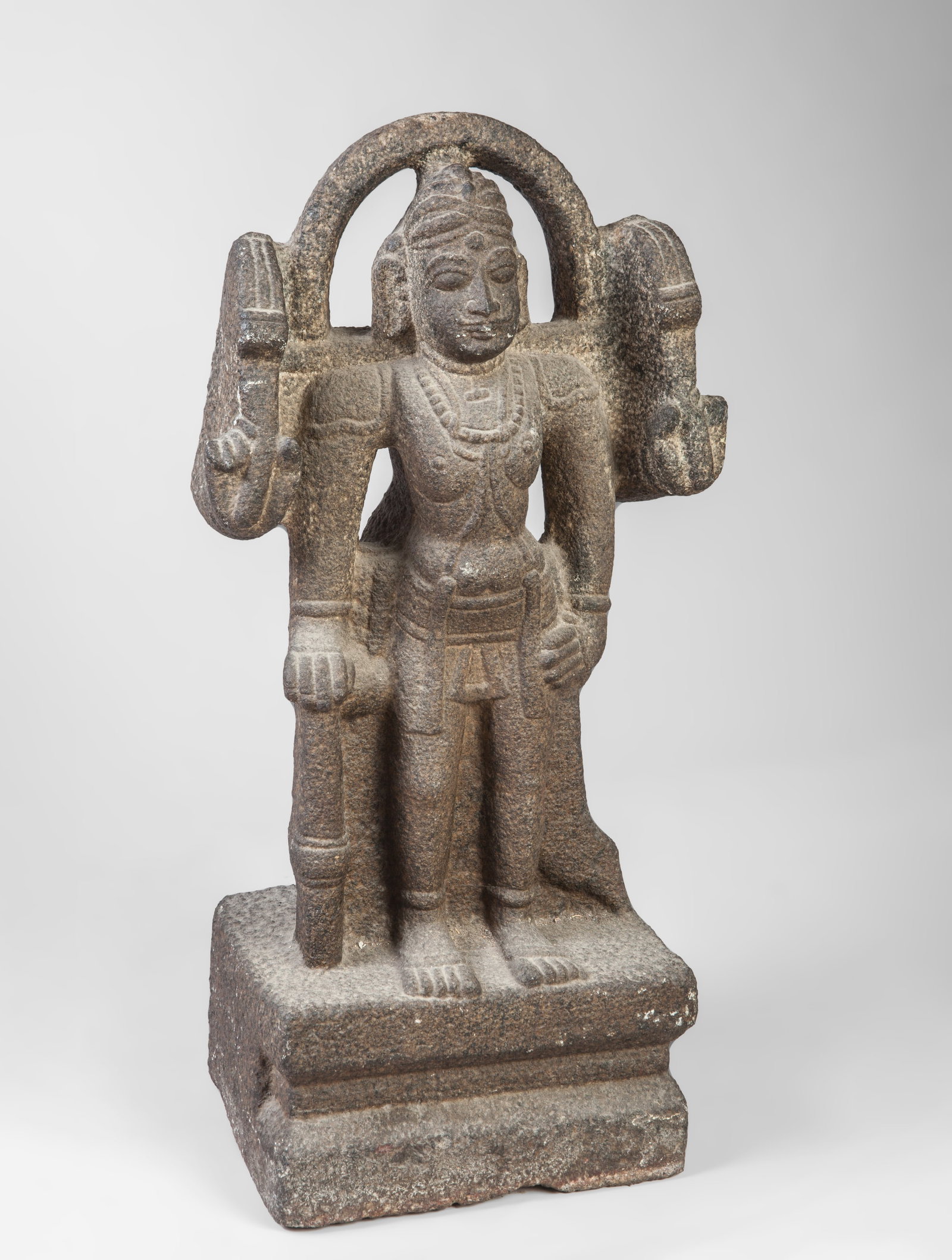 Virabhadra with mandorla, Vijayanagar school, 16th century: Carved gray sandstone. Measures 56 x 28 cm. Sculpture of Virabhadra, the warrior form of Shiva, depicted standing on a rectangular pedestal and surrounded by an architectural mandorla. The deity is sh