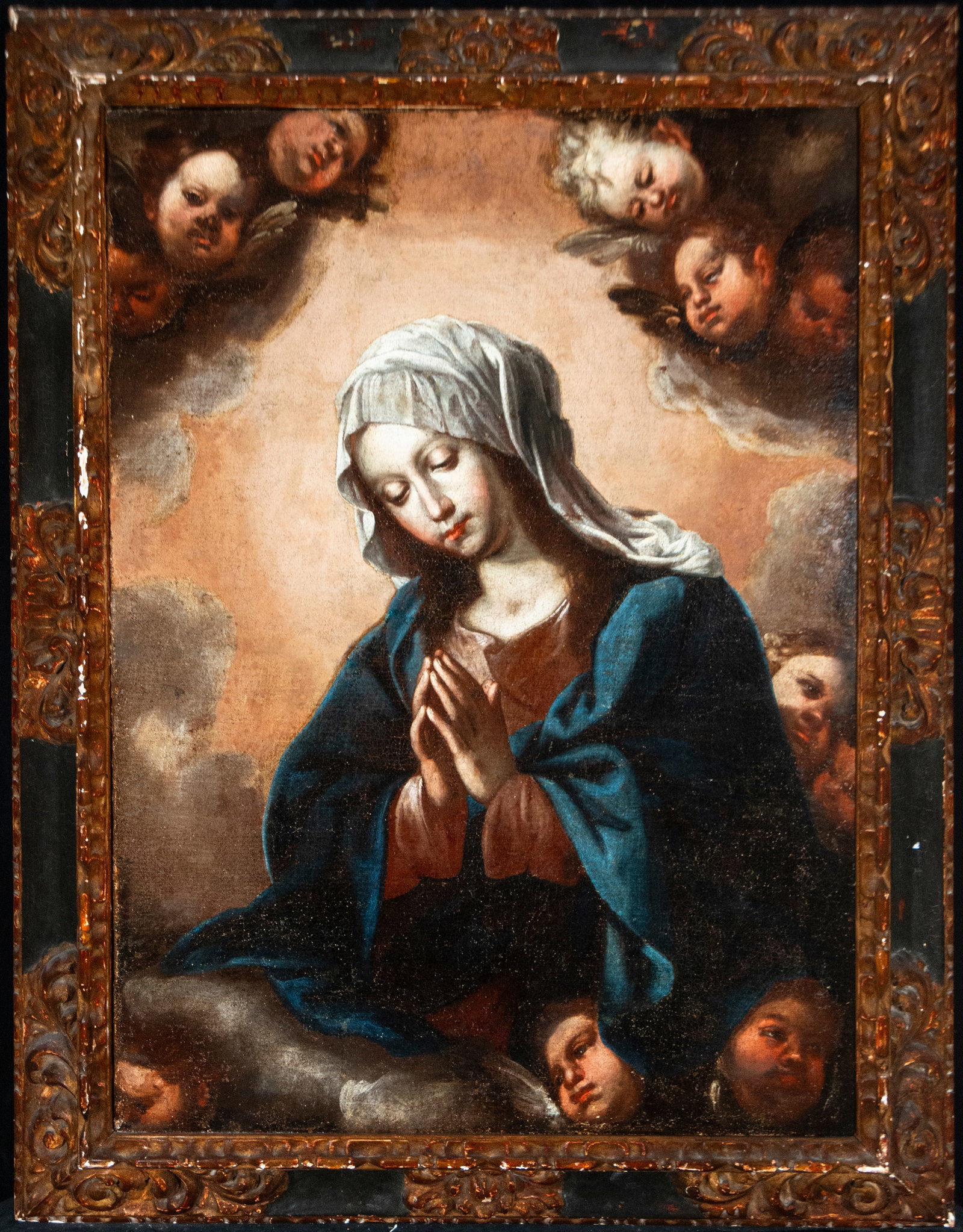 Virgin in prayer surrounded by angels. Spanish School. 17th Century: Oil on canvas. Dimensions without frame: 106 x 80 cm. Dimensions with frame: 126 x 99 cm. The Virgin, with her hands clasped and her head bowed, occupies the center of a glory of clouds and angelic he