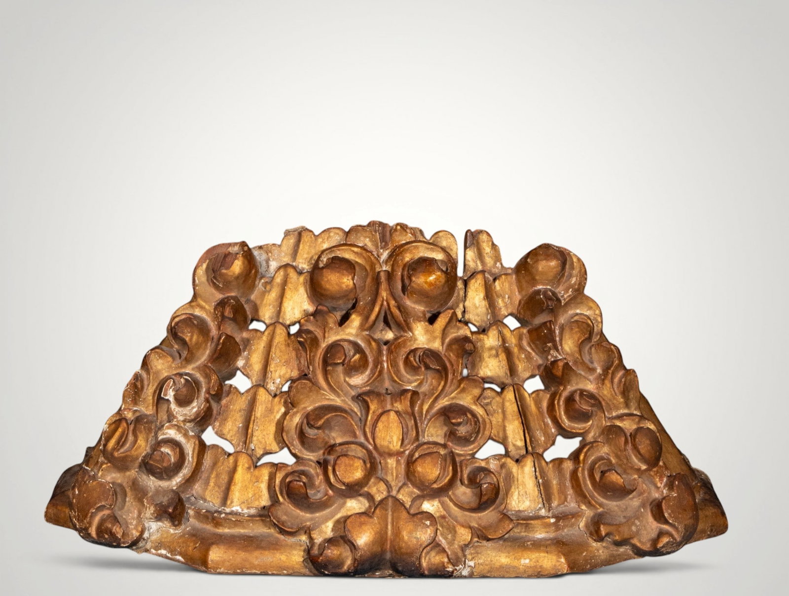 Baroque openwork crest. Hispanic School. 18th century: Carved and gilded wood. Measures 28 x 61 x 22 cm. Semicircular crest composed of scrolls, leaves, and openwork motifs arranged symmetrically. The vigorous carving and warm gilding place it within the 
